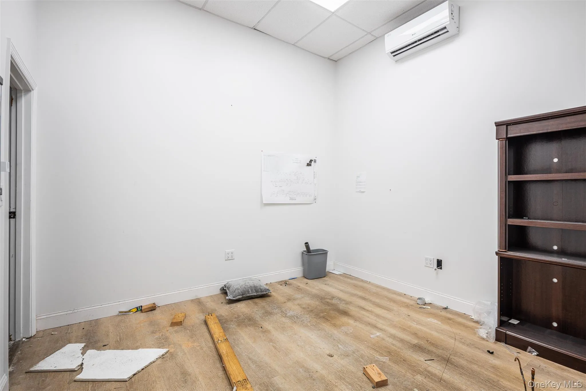 Back office with a drop ceiling, a mini split for heating / cooling, and wood finished floors Back office with a drop ceiling, a mini split for heating / cooling, and wood finished floors