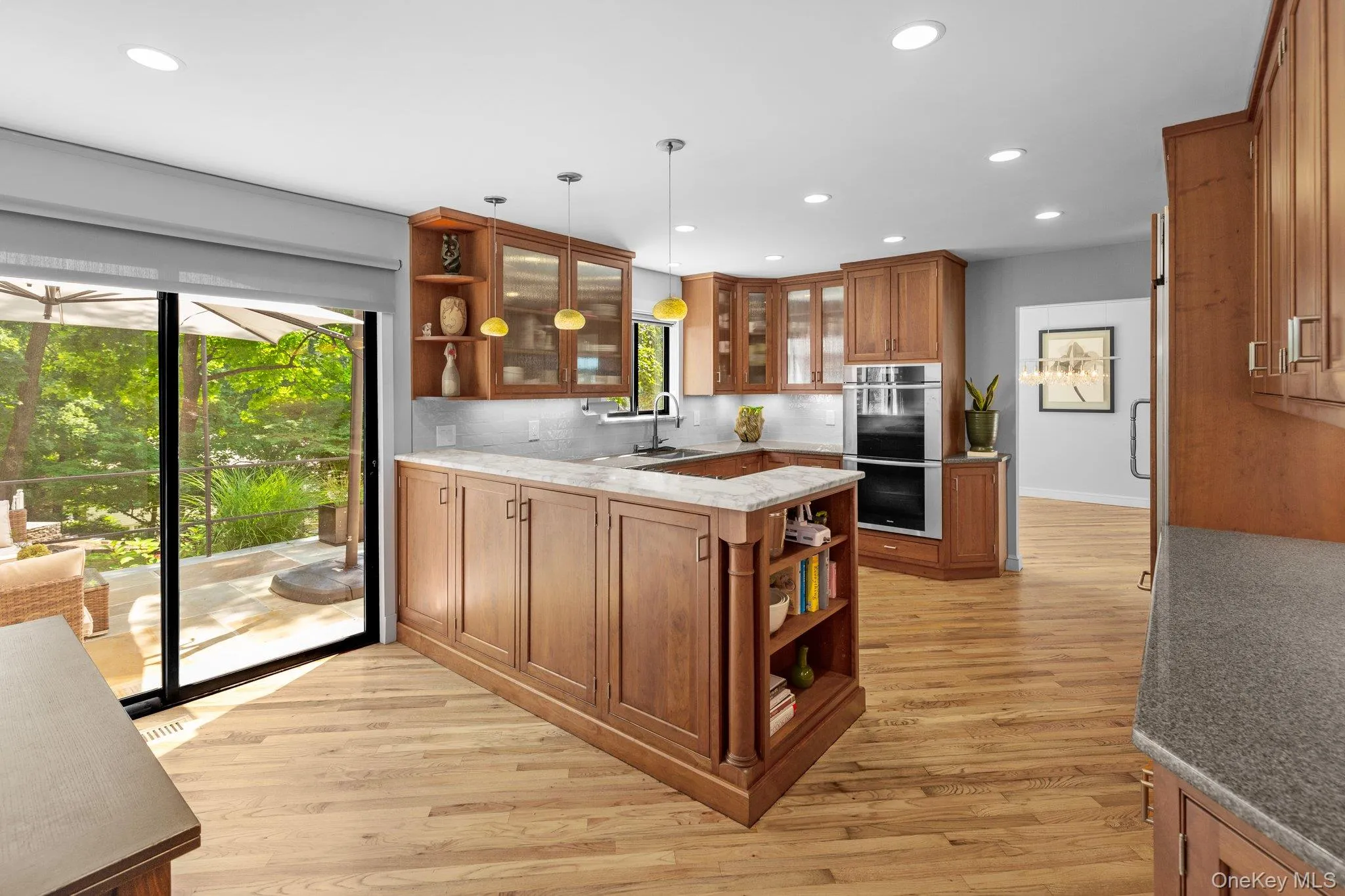 Kitchen featuring stainless steel double oven, brown cabinets, open shelves, and plenty of natural light Kitchen featuring stainless steel double oven, brown cabinets, open shelves, and plenty of natural light