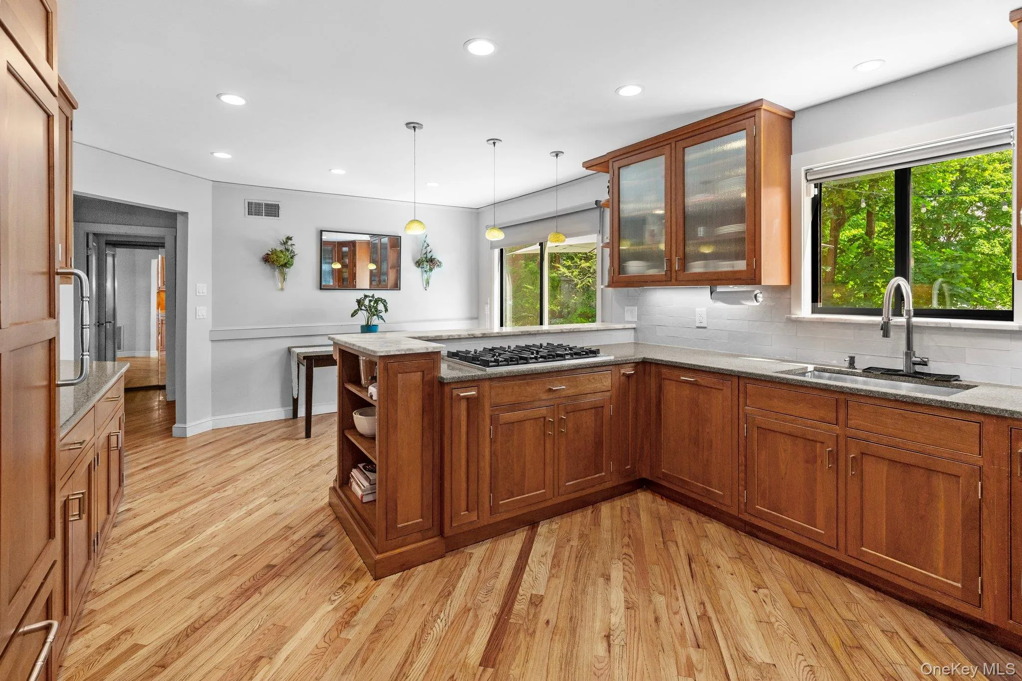 Kitchen with a sink, stainless steel gas stovetop, visible vents, a peninsula, and brown cabinetry Kitchen with a sink, stainless steel gas stovetop, visible vents, a peninsula, and brown cabinetry