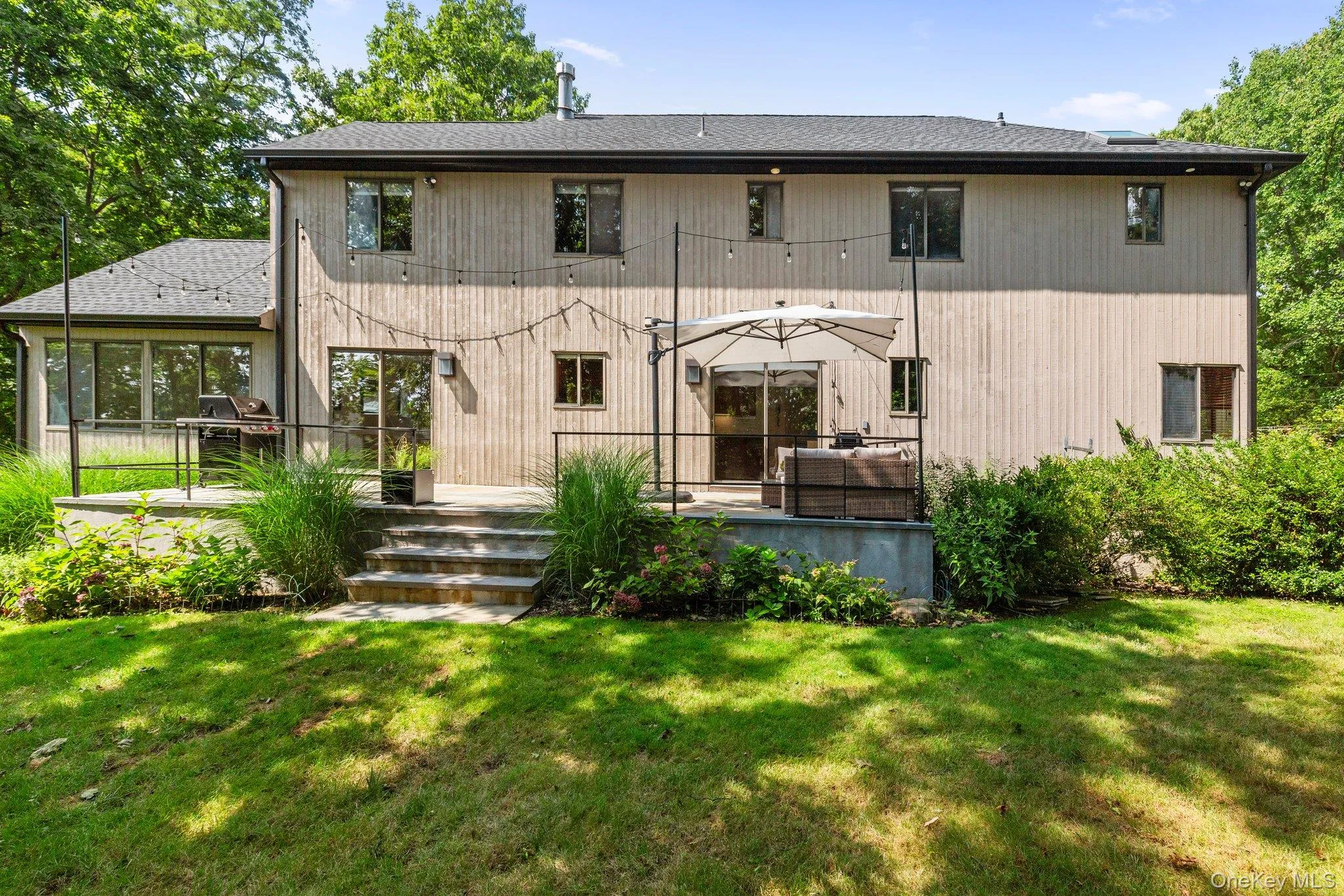 Rear view of house with a deck and a lawn Rear view of house with a deck and a lawn
