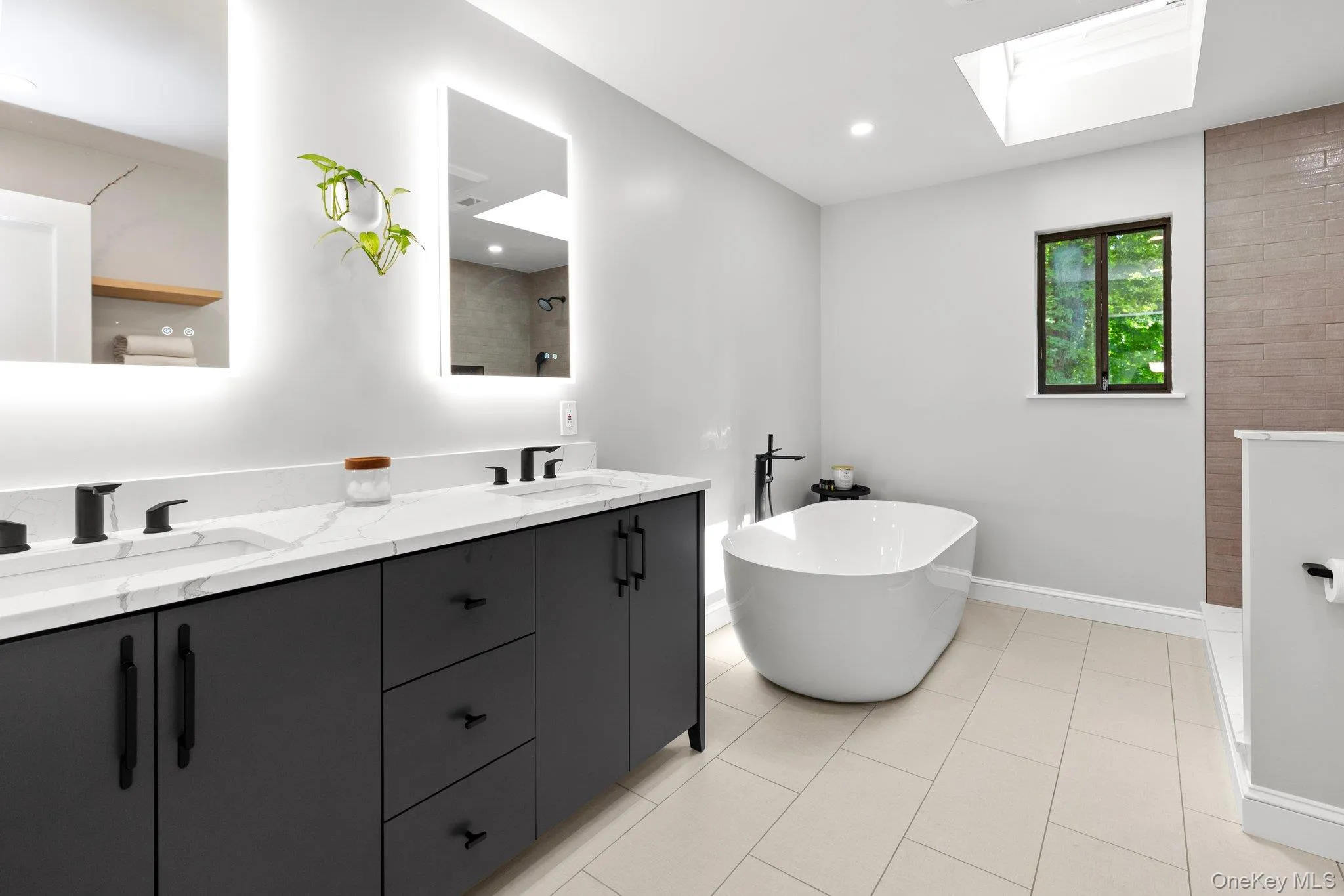 Bathroom with a soaking tub, a skylight, double vanity, tiled shower, and a sink Bathroom with a soaking tub, a skylight, double vanity, tiled shower, and a sink