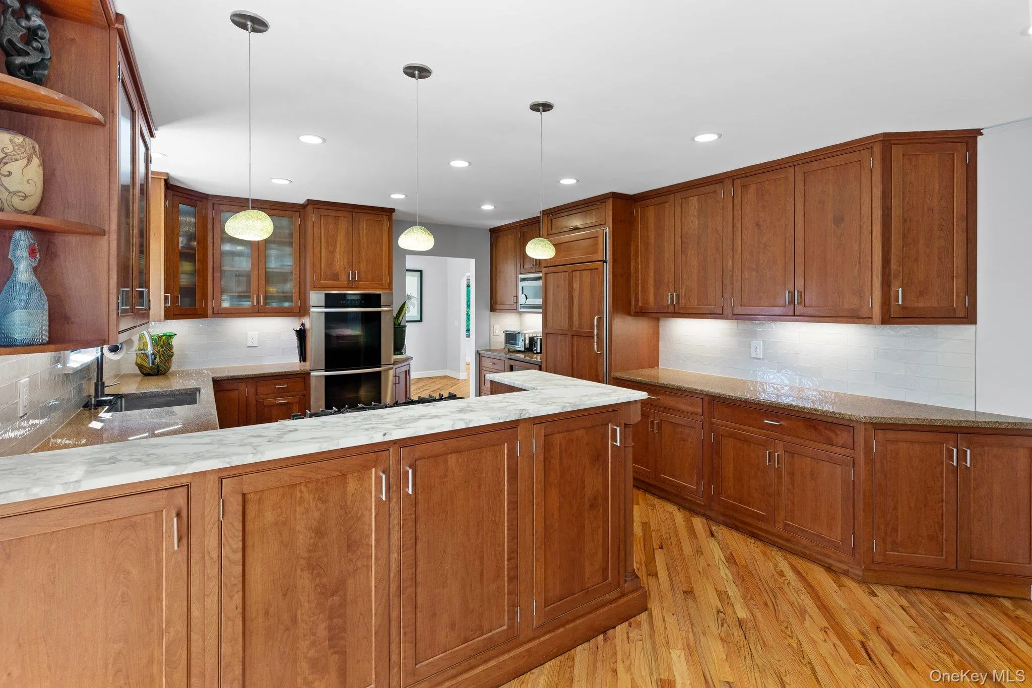 Kitchen featuring open shelves, brown cabinetry, a sink, and stainless steel double oven Kitchen featuring open shelves, brown cabinetry, a sink, and stainless steel double oven