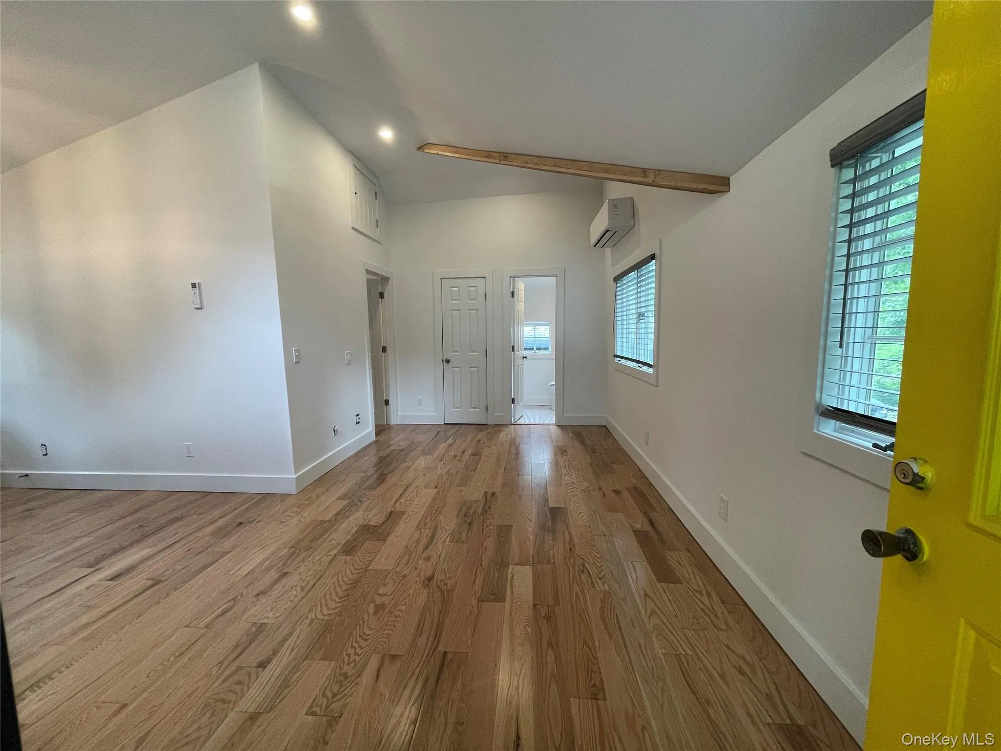 Foyer featuring an AC wall unit, wood finished floors, baseboards, recessed lighting, and lofted ceiling Foyer featuring an AC wall unit, wood finished floors, baseboards, recessed lighting, and lofted ceiling