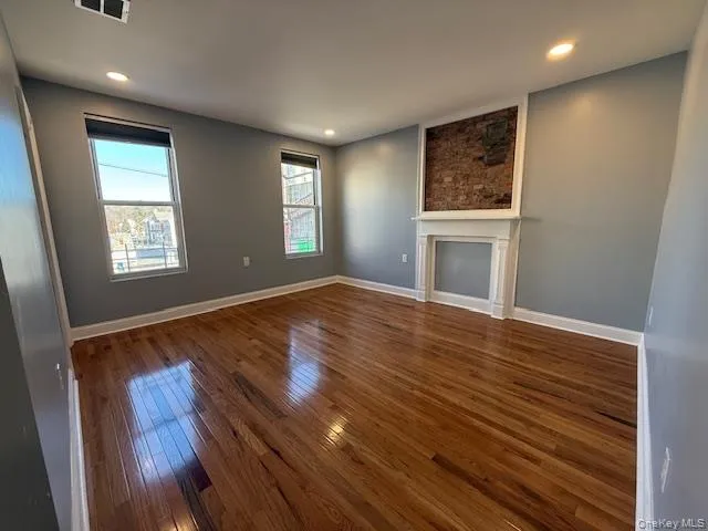 Unfurnished living room featuring wood-type flooring, recessed lighting, and a fireplace Unfurnished living room featuring wood-type flooring, recessed lighting, and a fireplace