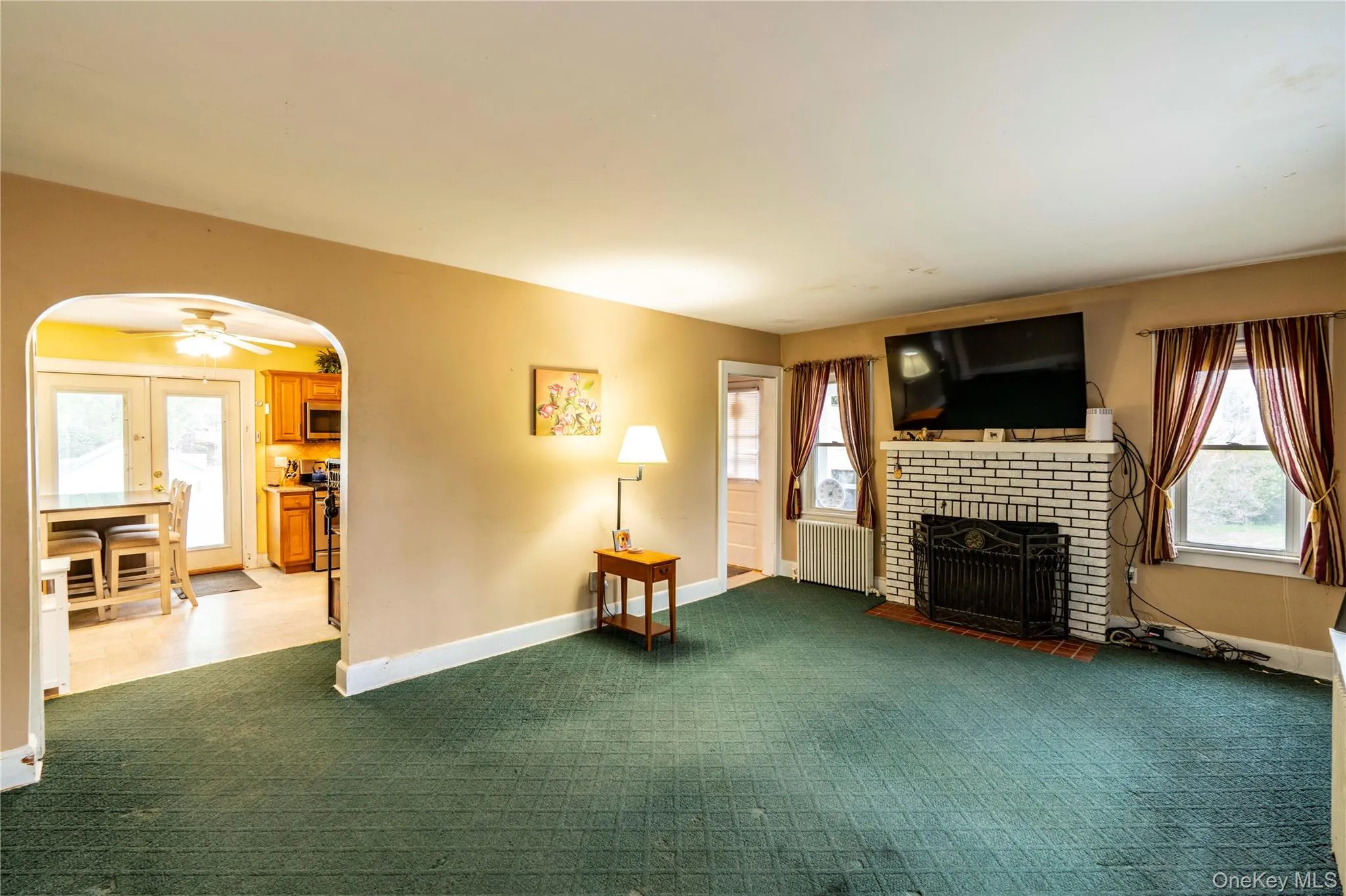 Living area featuring a white brick fireplace with an iron grate, Lots of windows and hardwood floors. Living area featuring a white brick fireplace with an iron grate, Lots of windows and hardwood floors.