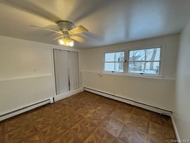 Unfurnished bedroom featuring baseboard heating and ceiling fan Unfurnished bedroom featuring baseboard heating and ceiling fan
