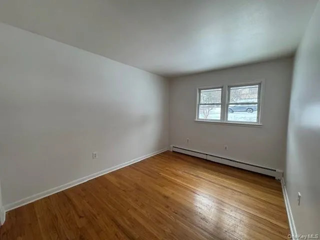 Empty room with a baseboard heating unit and light wood-type flooring Empty room with a baseboard heating unit and light wood-type flooring
