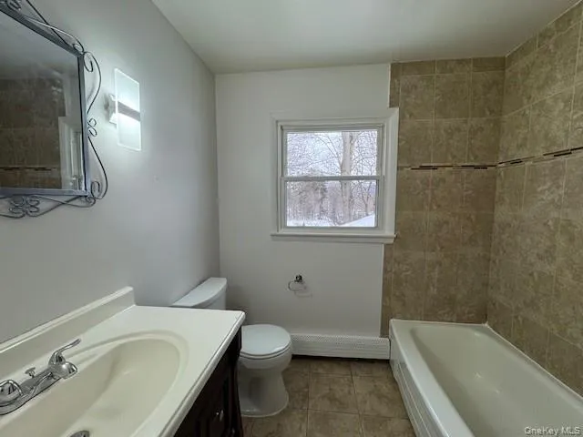 Bathroom featuring vanity, a baseboard heating unit, and light tile patterned flooring Bathroom featuring vanity, a baseboard heating unit, and light tile patterned flooring