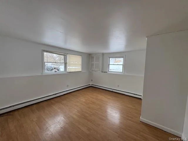 Spare room with light wood-type flooring and a baseboard radiator Spare room with light wood-type flooring and a baseboard radiator