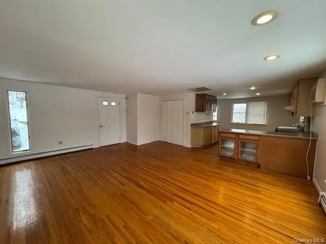 Unfurnished living room featuring dark wood-style flooring, recessed lighting, and a baseboard heating unit Unfurnished living room featuring dark wood-style flooring, recessed lighting, and a baseboard heating unit