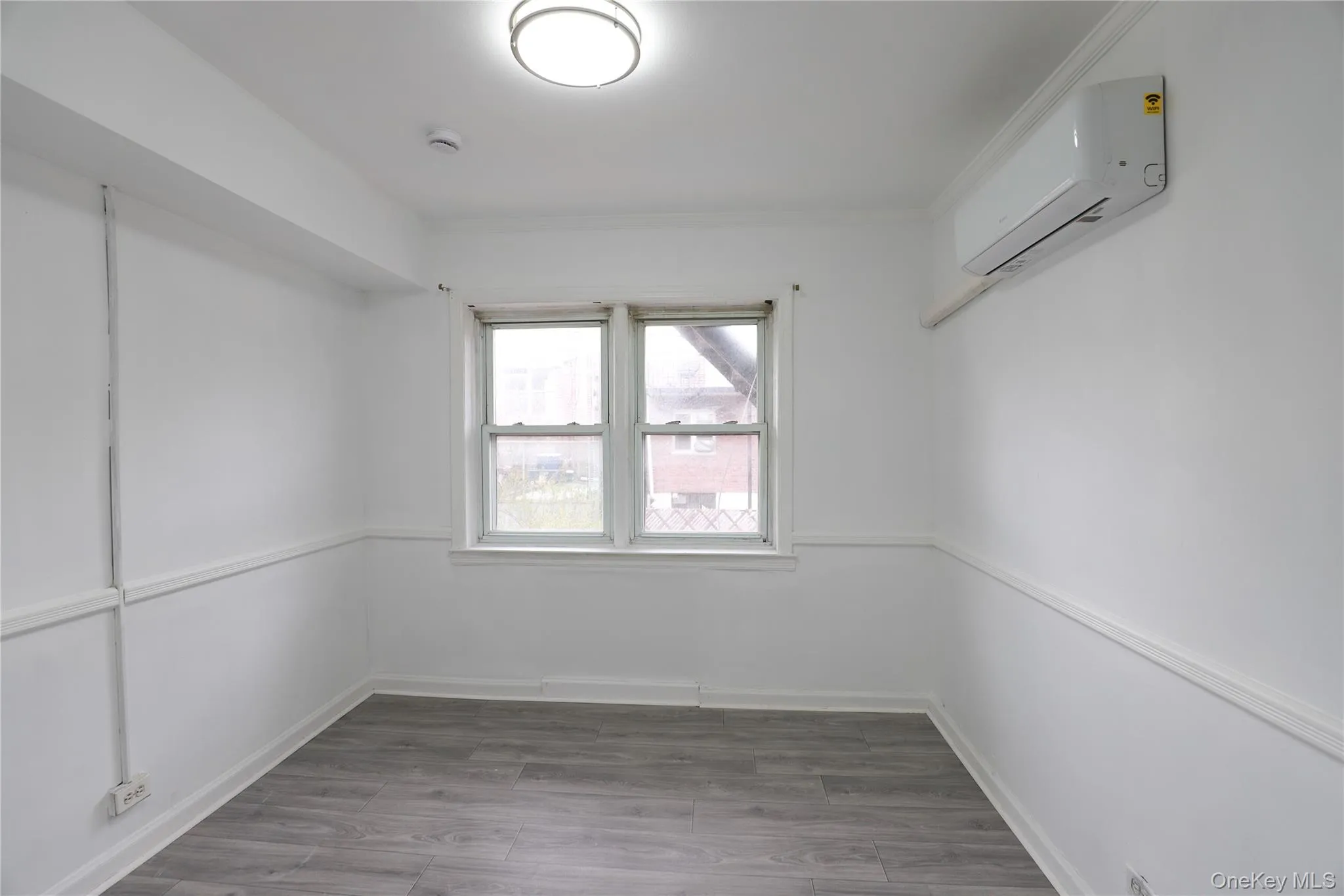Empty room featuring wood finished floors and a wall mounted mini split Empty room featuring wood finished floors and a wall mounted mini split