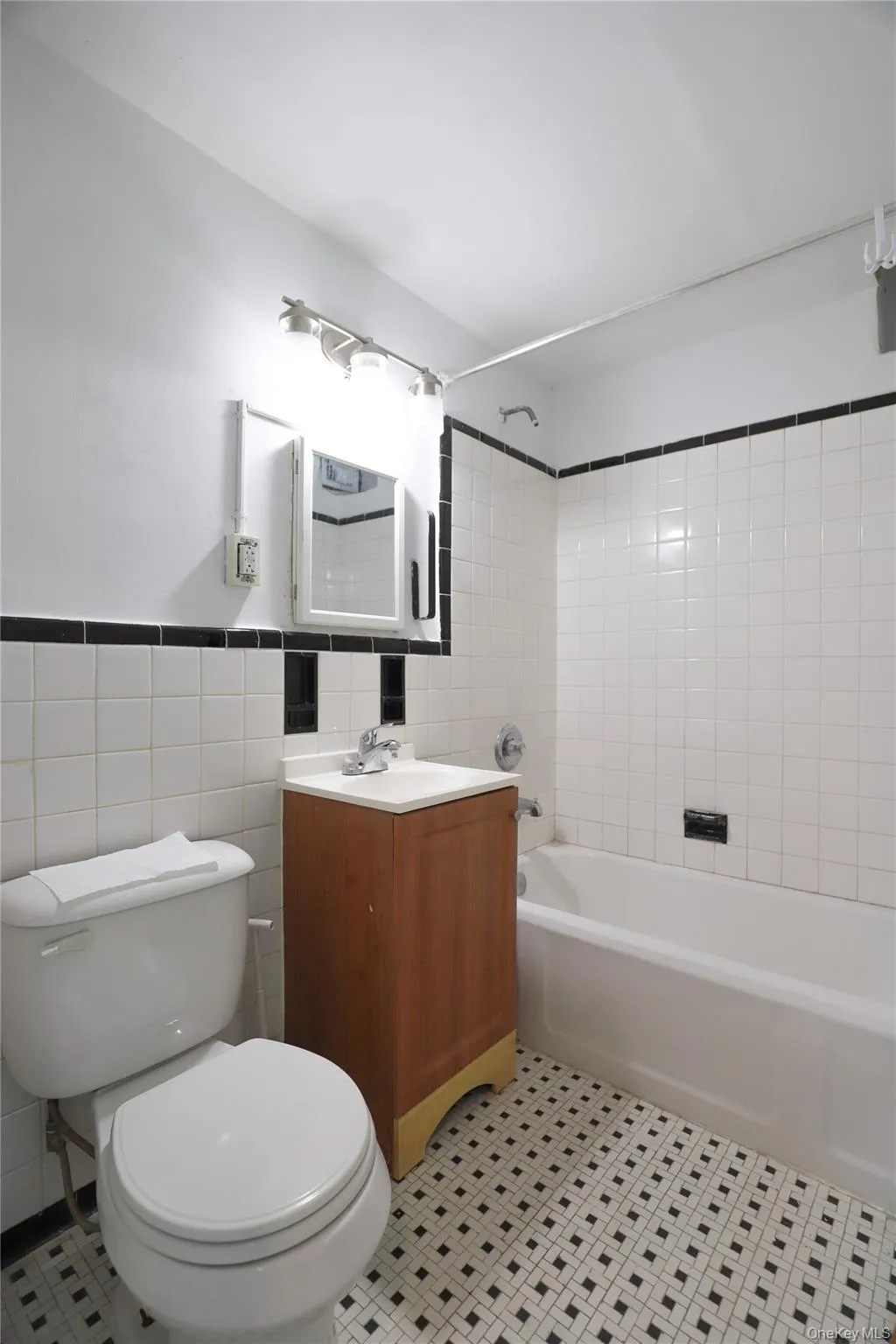 Full bathroom with vanity, tile walls, shower / washtub combination, light tile patterned floors, and wainscoting Full bathroom with vanity, tile walls, shower / washtub combination, light tile patterned floors, and wainscoting