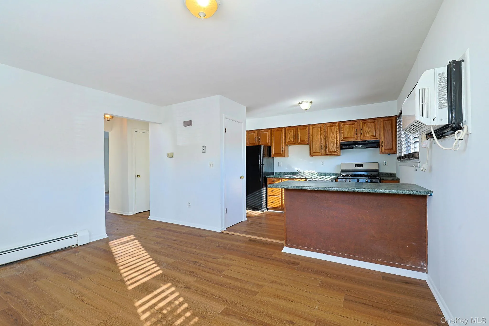 Kitchen with dark countertops, wood finish cabinetry, dark wood-style floors, freestanding refrigerator, and gas range Kitchen with dark countertops, wood finish cabinetry, dark wood-style floors, freestanding refrigerator, and gas range