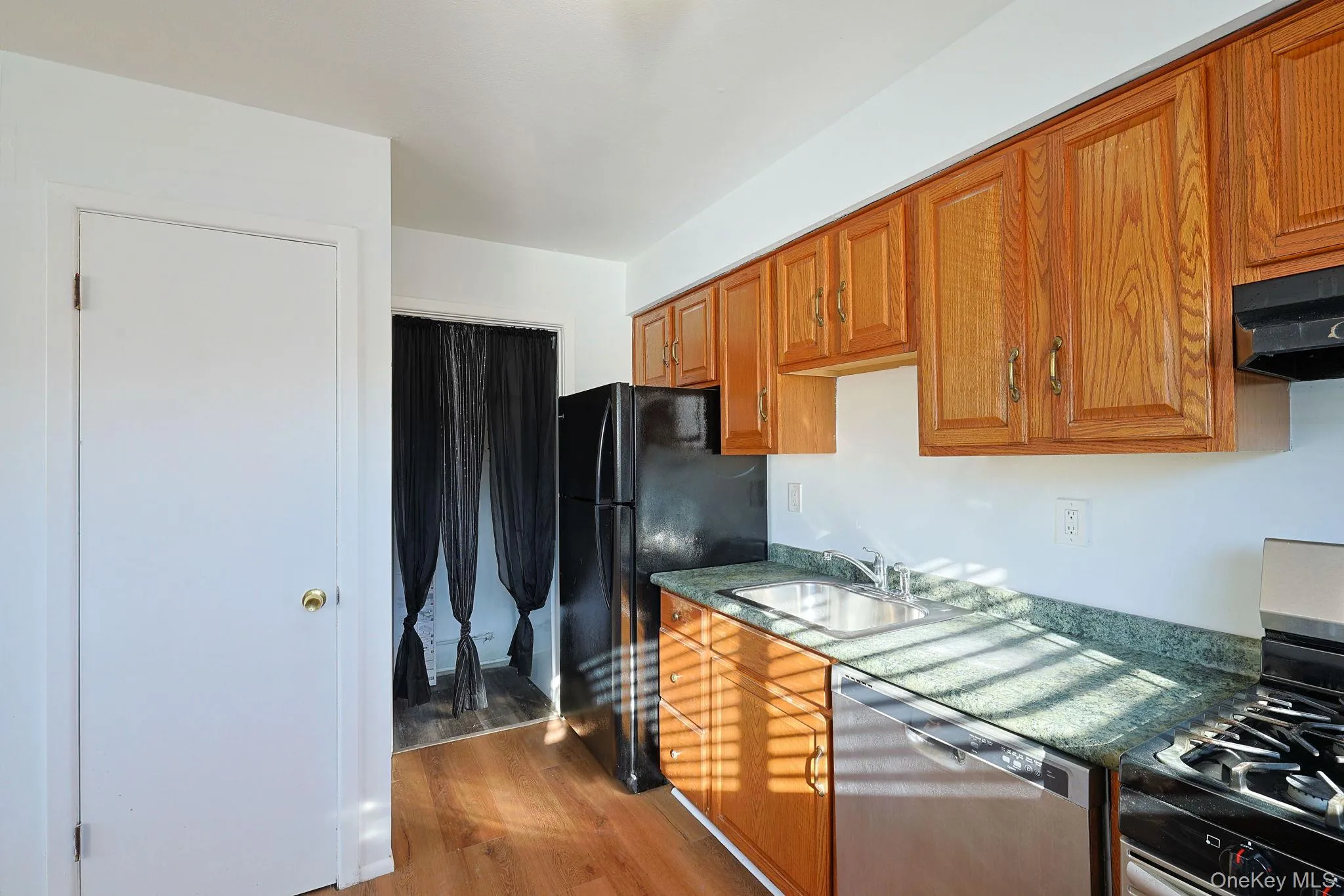 Kitchen with stainless steel appliances, wood finish cabinets, and light wood-style flooring Kitchen with stainless steel appliances, wood finish cabinets, and light wood-style flooring