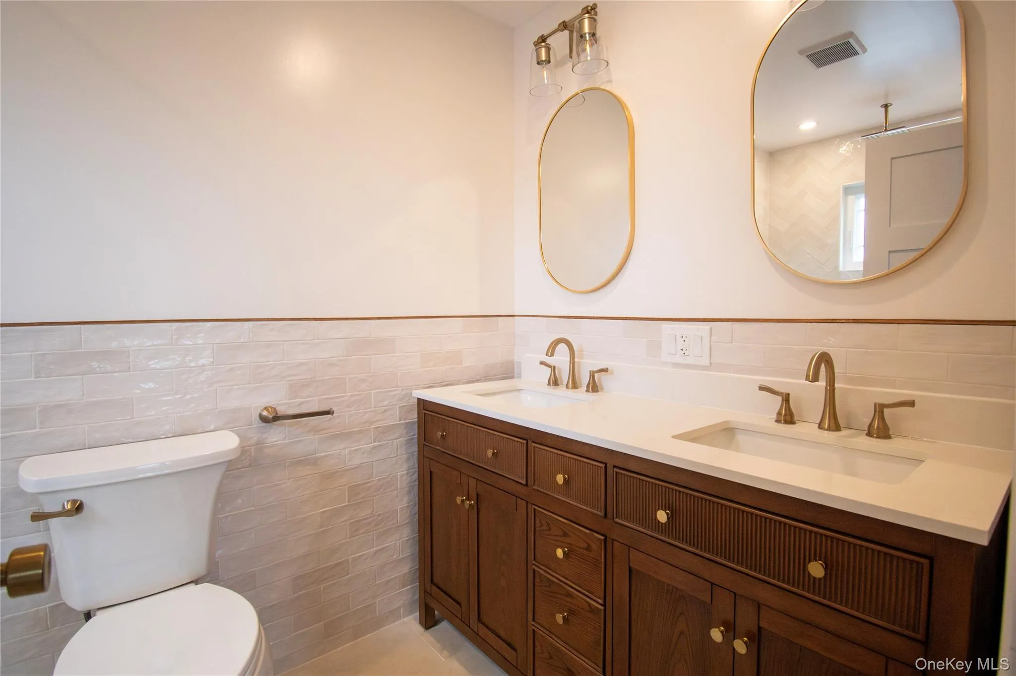 Full bathroom with tile walls, double vanity, and wainscoting Full bathroom with tile walls, double vanity, and wainscoting