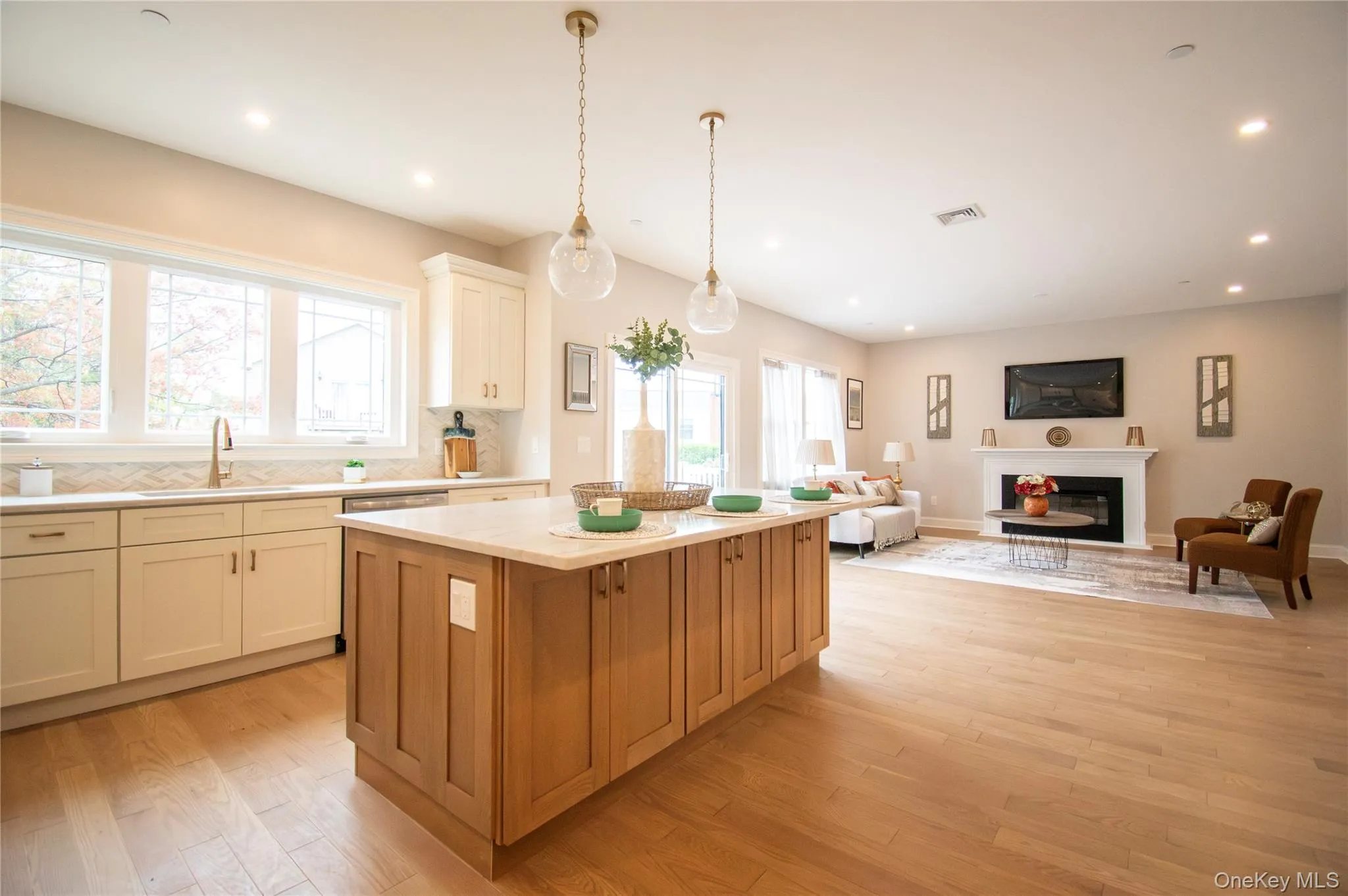 Kitchen featuring decorative backsplash, a kitchen island, pendant lighting, light wood finished floors, and open floor plan Kitchen featuring decorative backsplash, a kitchen island, pendant lighting, light wood finished floors, and open floor plan