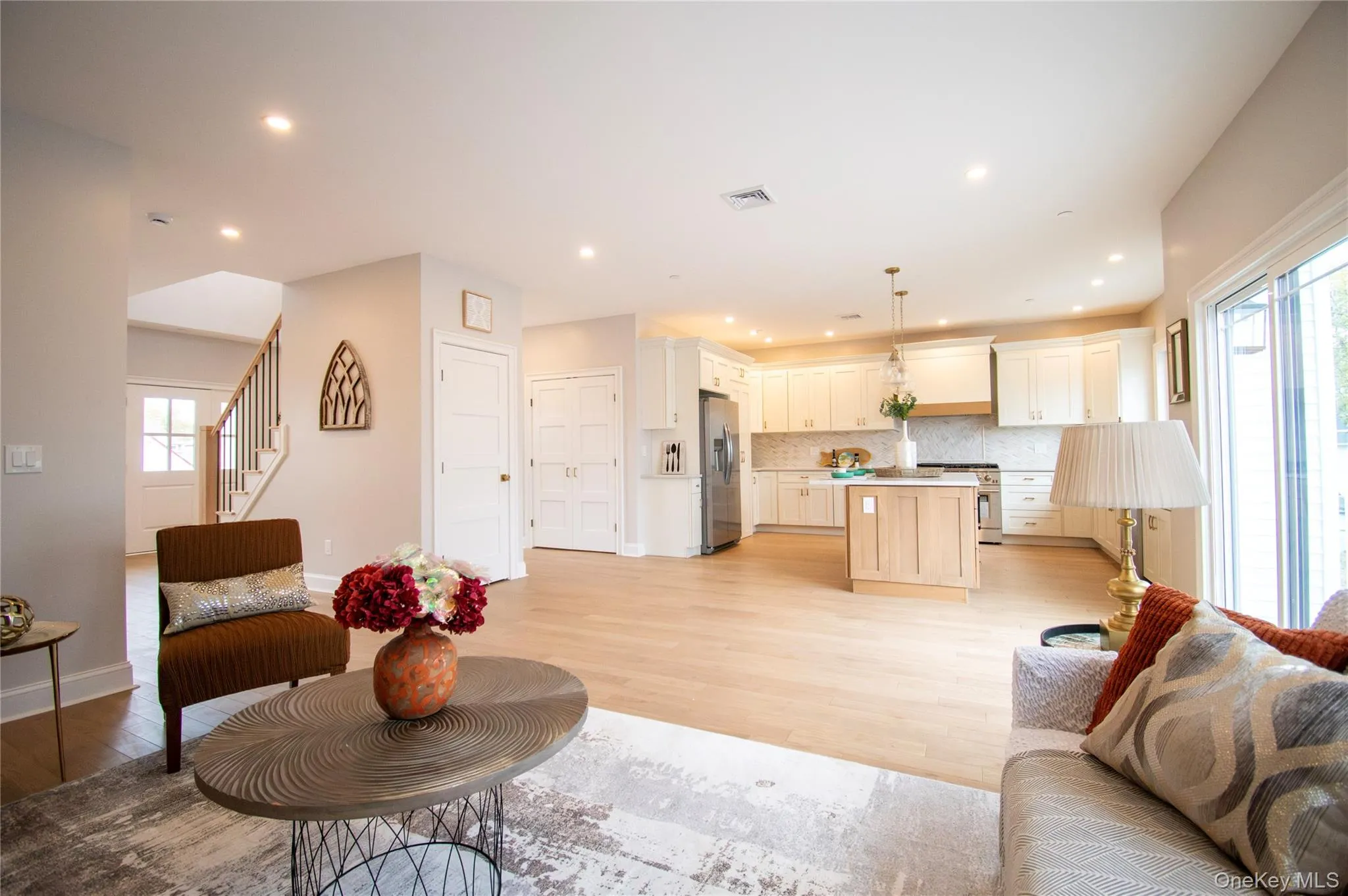 Living area featuring light wood-style flooring, recessed lighting, and stairs Living area featuring light wood-style flooring, recessed lighting, and stairs