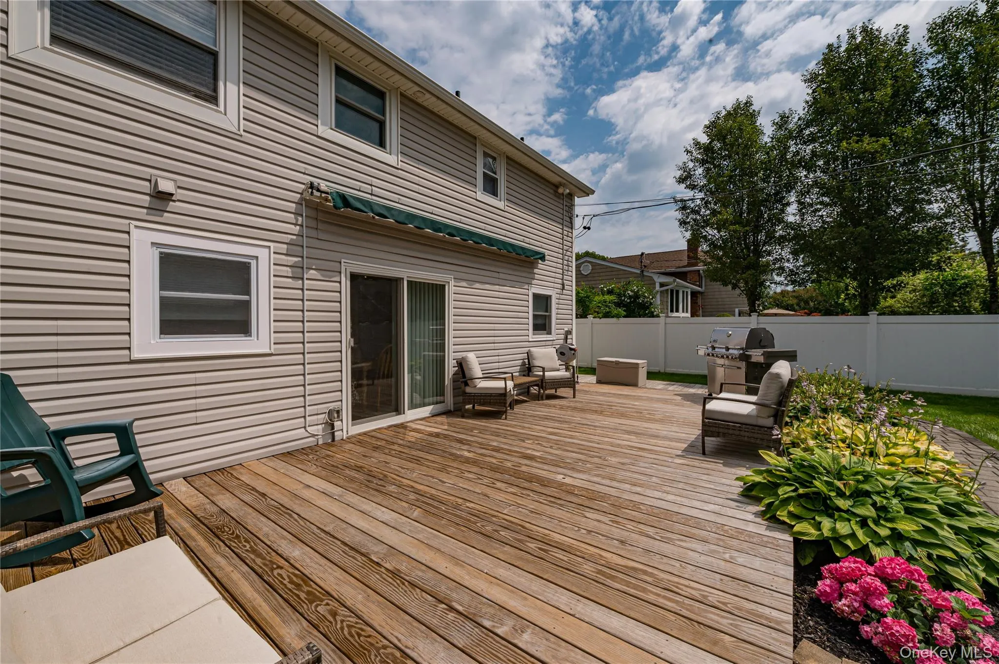 Expansive wood-finish deck with integrated landscaping, offering direct access to the interior via sliding glass doors Expansive wood-finish deck with integrated landscaping, offering direct access to the interior via sliding glass doors