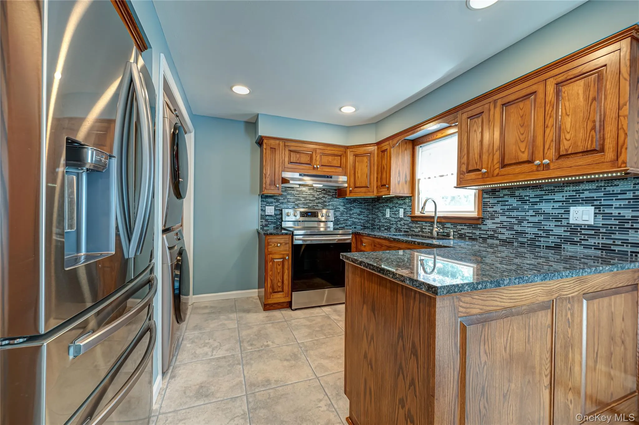 Kitchen featuring wood cabinetry, dark speckled countertops, and a full tile backsplash Kitchen featuring wood cabinetry, dark speckled countertops, and a full tile backsplash