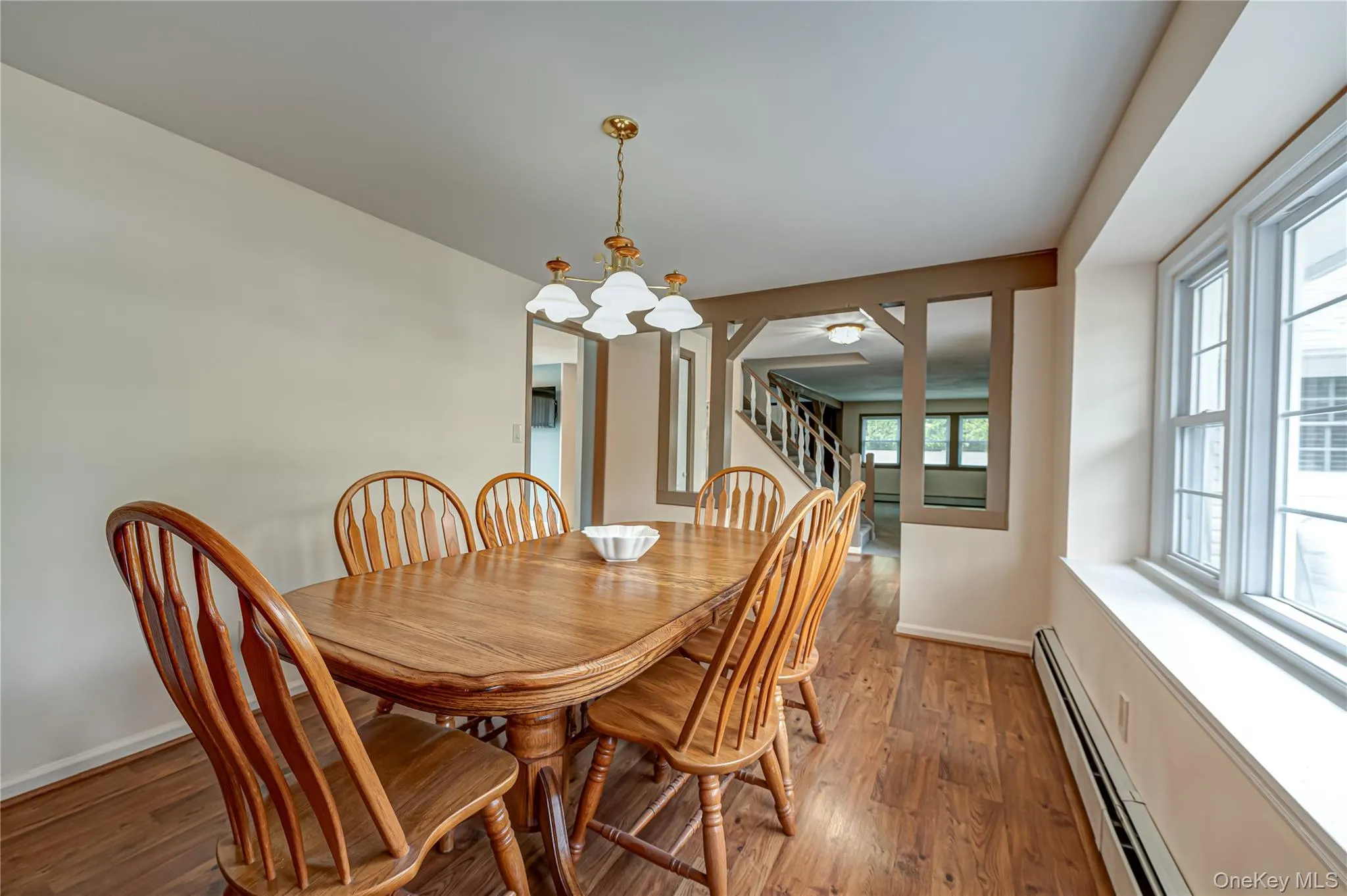 Dining area featuring wood-finish flooring, a multi-pane window, and an open entryway with exposed wood beams Dining area featuring wood-finish flooring, a multi-pane window, and an open entryway with exposed wood beams
