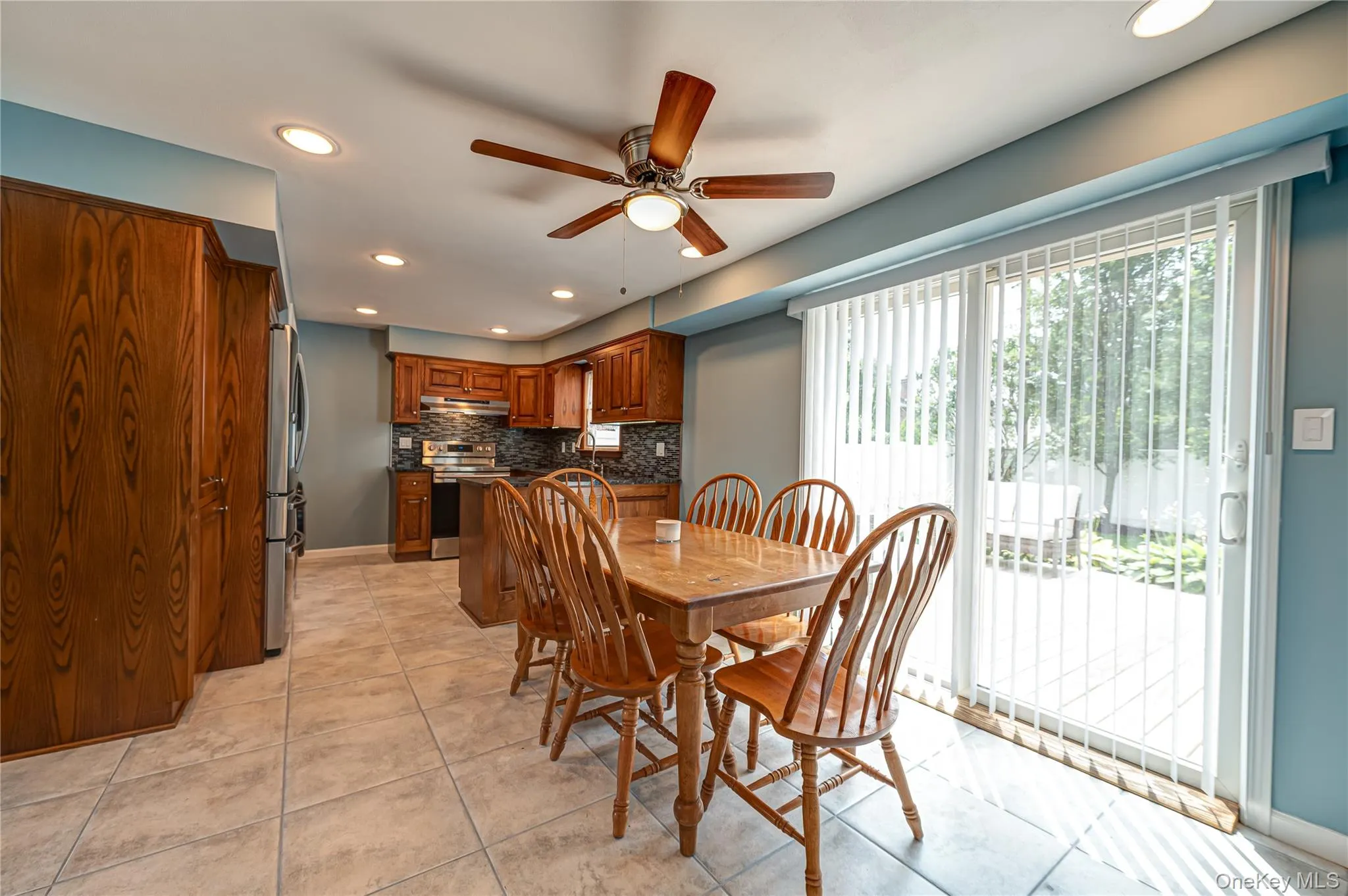 Kitchen and dining area featuring wood cabinetry, stainless steel appliances, and a mosaic tile backsplash Kitchen and dining area featuring wood cabinetry, stainless steel appliances, and a mosaic tile backsplash