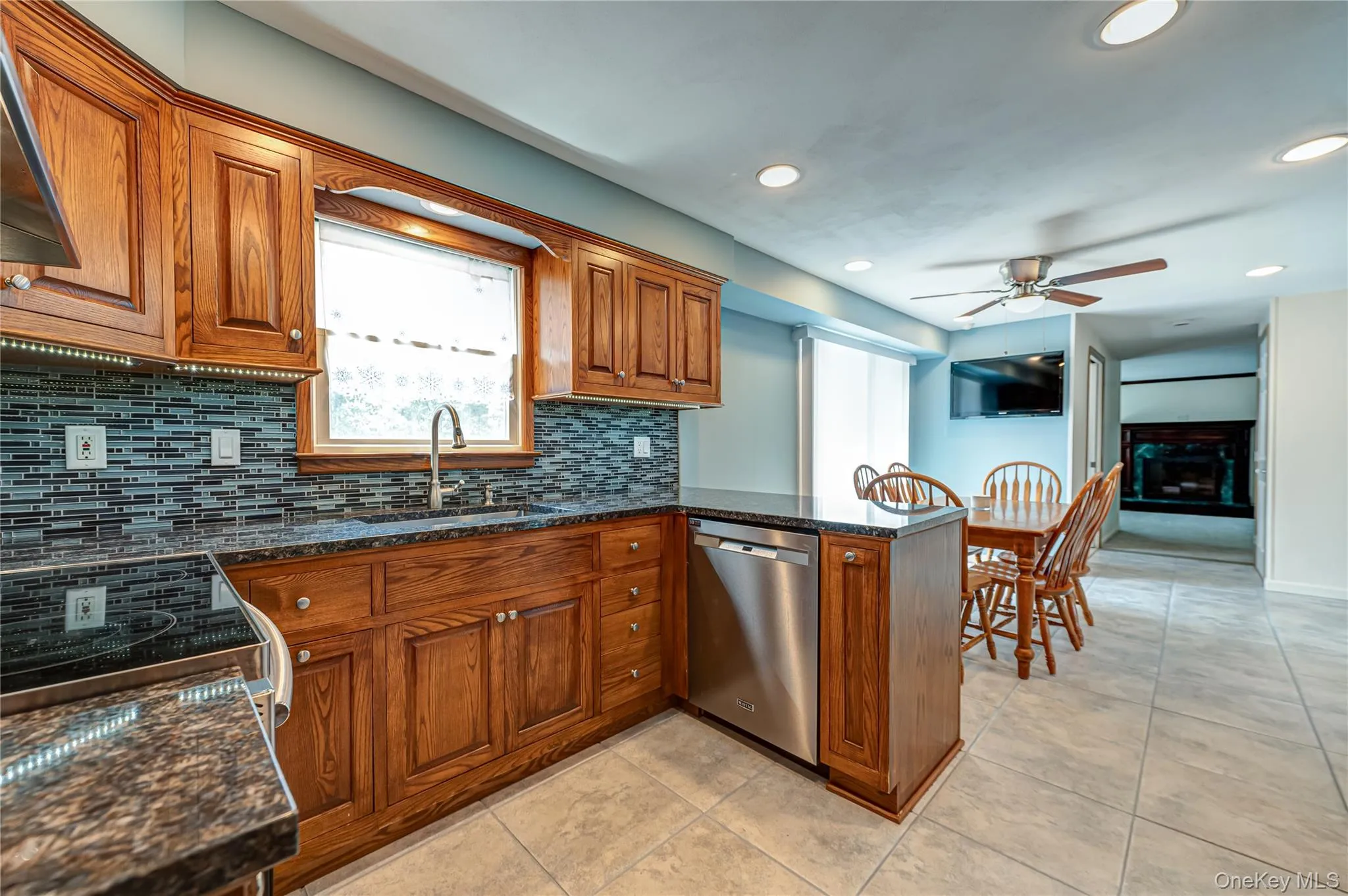 Kitchen featuring solid wood cabinetry, a mosaic tile backsplash, dark stone countertops, and recessed lighting Kitchen featuring solid wood cabinetry, a mosaic tile backsplash, dark stone countertops, and recessed lighting