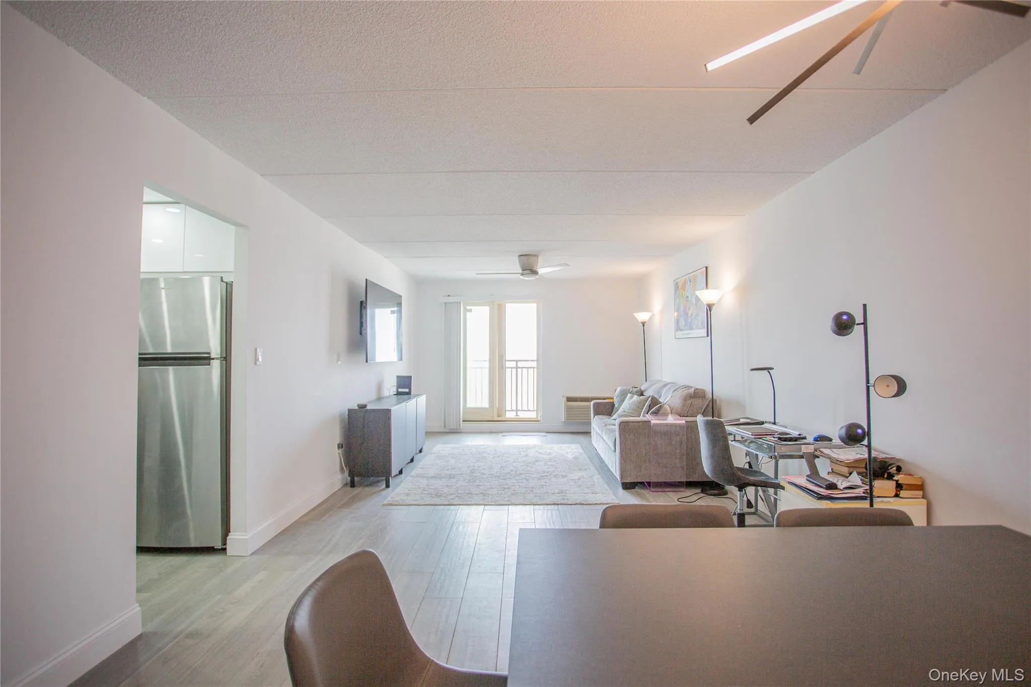 Living room featuring ceiling fan, light wood-style flooring, a textured ceiling, and an office area Living room featuring ceiling fan, light wood-style flooring, a textured ceiling, and an office area
