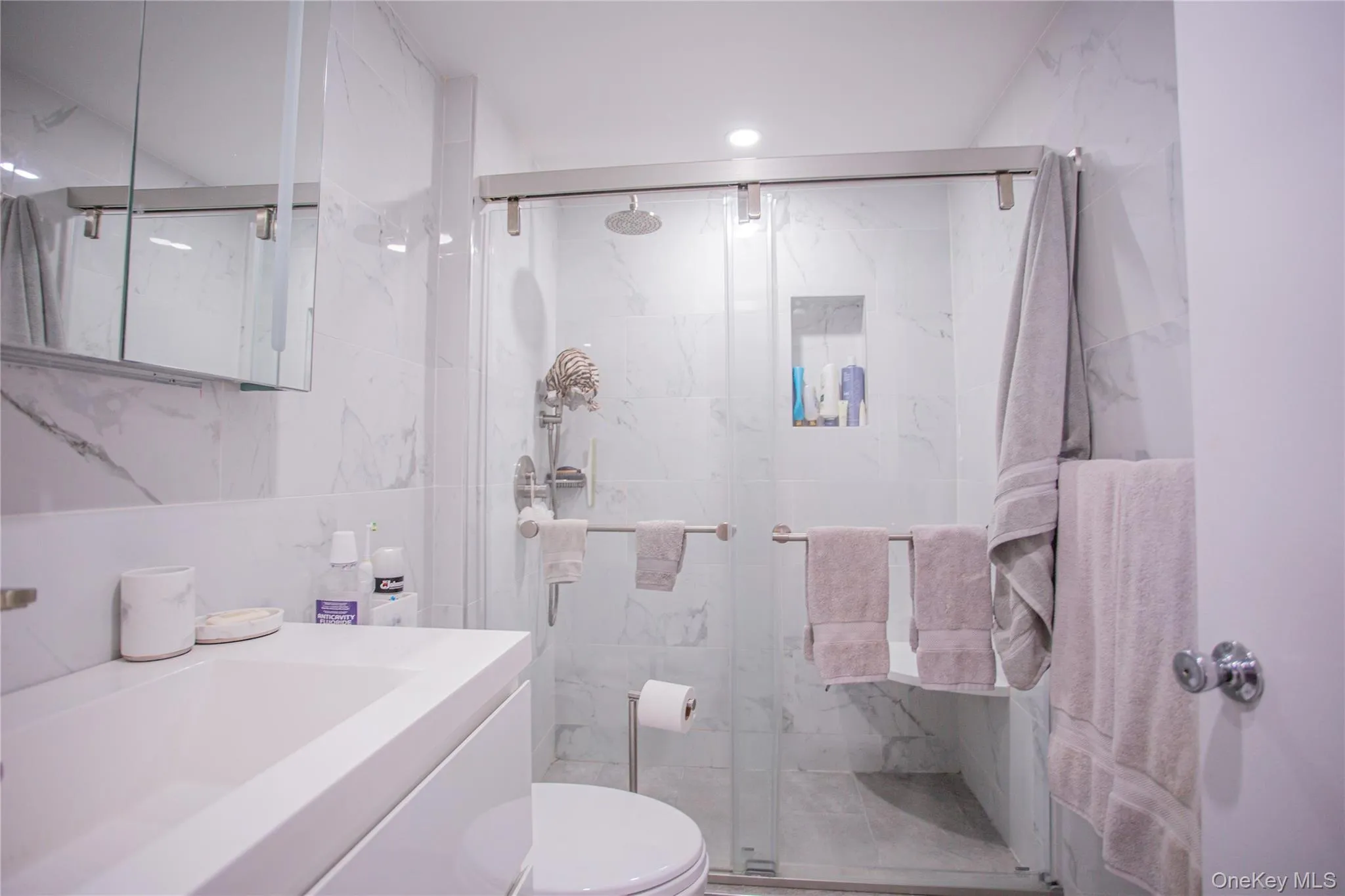 Full bathroom with tile walls, vanity, and a marble finish shower Full bathroom with tile walls, vanity, and a marble finish shower