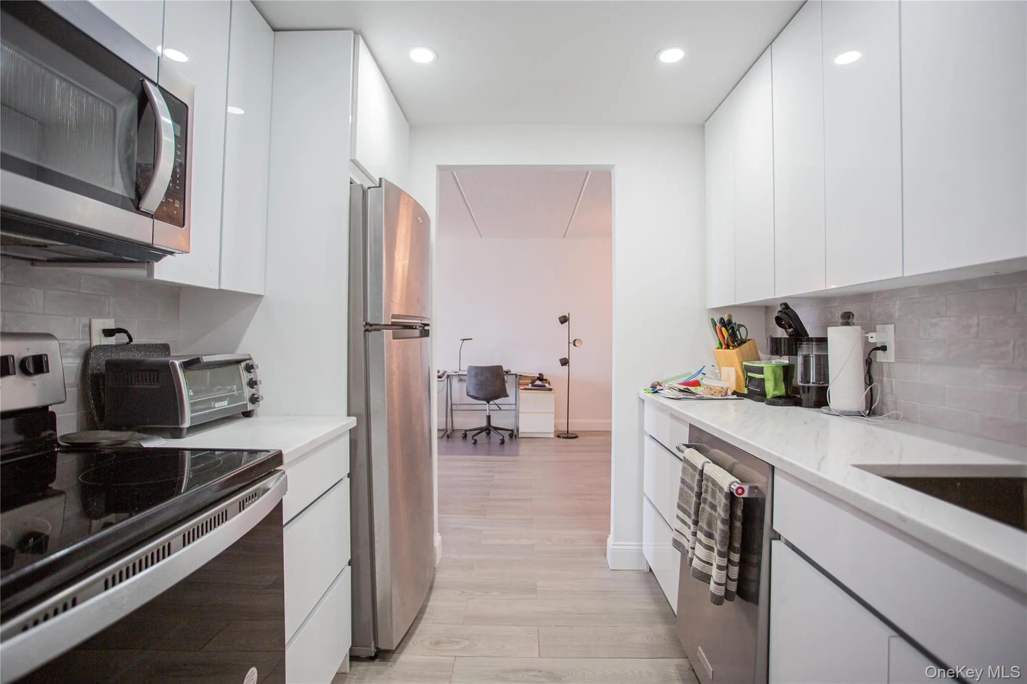 Kitchen featuring tasteful backsplash, stainless steel appliances, modern cabinets, white cabinetry, and an office area Kitchen featuring tasteful backsplash, stainless steel appliances, modern cabinets, white cabinetry, and an office area
