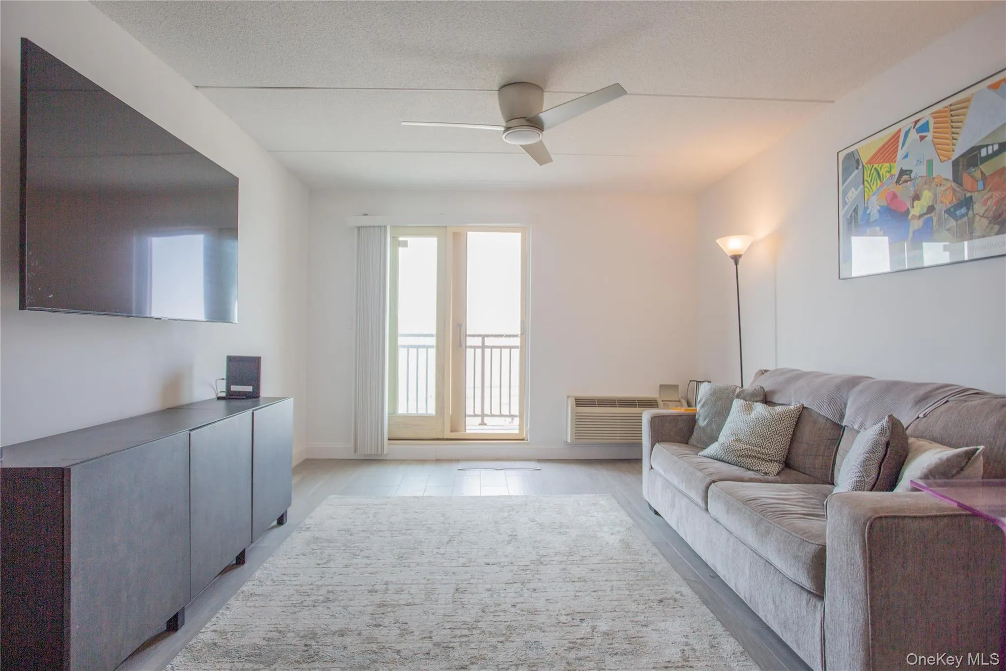 Living area with a textured ceiling, ceiling fan, and light wood finished floors Living area with a textured ceiling, ceiling fan, and light wood finished floors