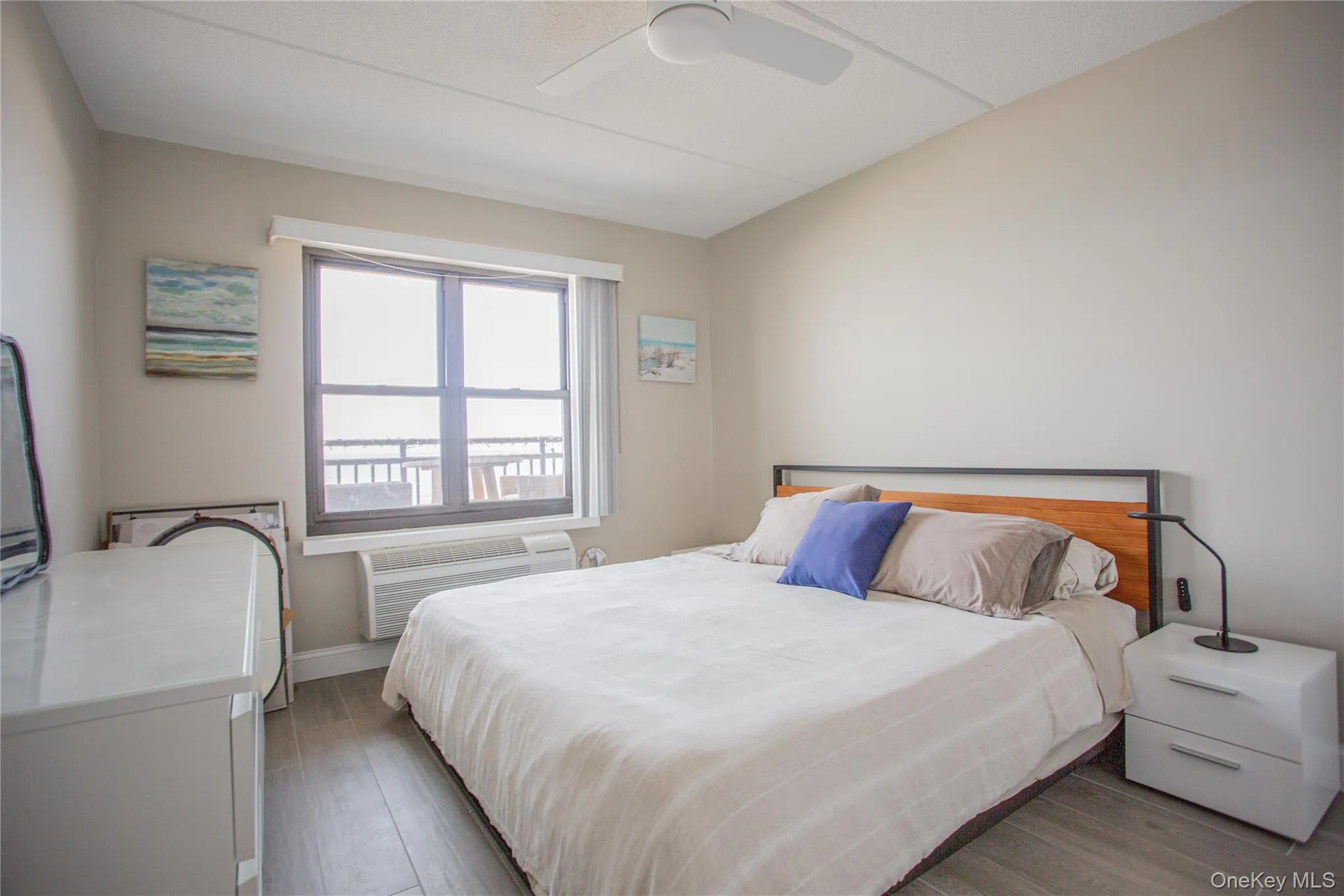 Bedroom with wood finished floors, ceiling fan, and a wall mounted AC Bedroom with wood finished floors, ceiling fan, and a wall mounted AC