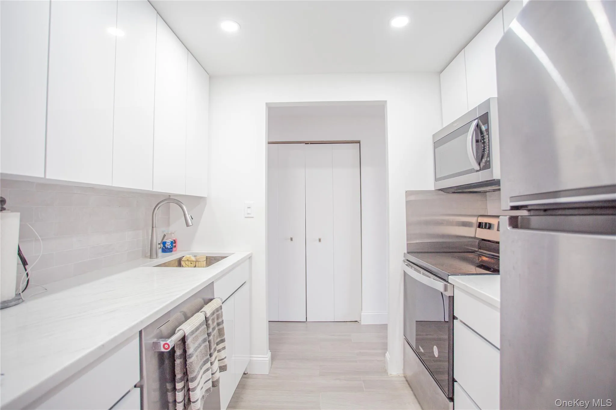 Kitchen featuring appliances with stainless steel finishes, modern cabinets, tasteful backsplash, white cabinetry, and recessed lighting Kitchen featuring appliances with stainless steel finishes, modern cabinets, tasteful backsplash, white cabinetry, and recessed lighting