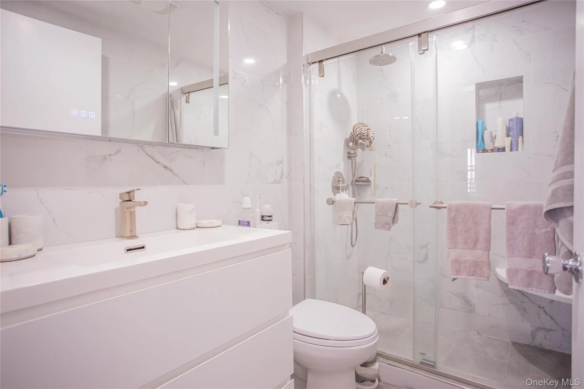 Bathroom with tile walls, vanity, a marble finish shower, and recessed lighting Bathroom with tile walls, vanity, a marble finish shower, and recessed lighting