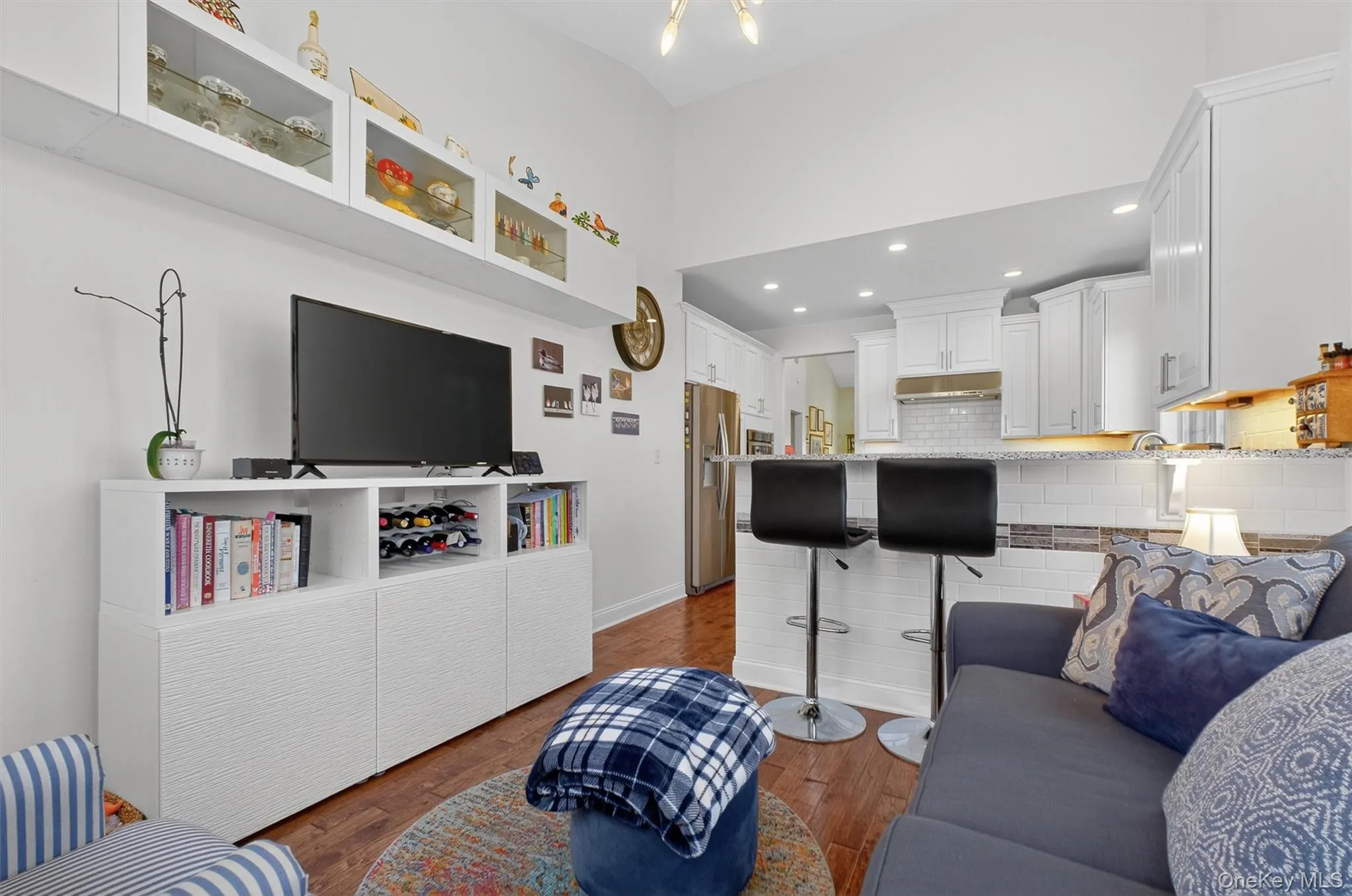 Living area with dark wood-style flooring, recessed lighting, and a high ceiling Living area with dark wood-style flooring, recessed lighting, and a high ceiling