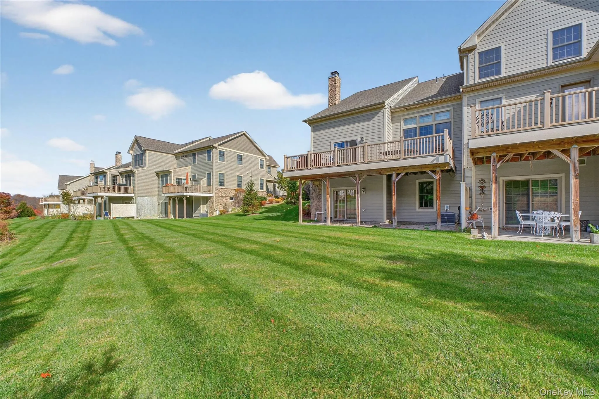 Rear view of property with a yard, a chimney, a patio area, a residential view, and a wooden deck Rear view of property with a yard, a chimney, a patio area, a residential view, and a wooden deck