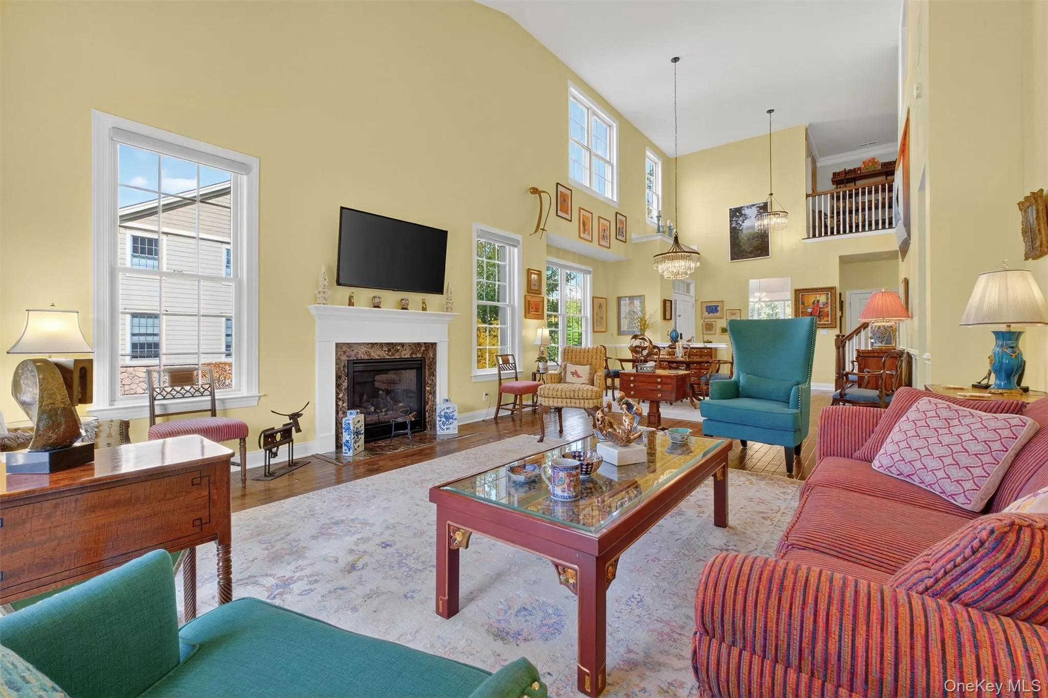 Living area featuring wood finished floors, a premium fireplace, and a high ceiling Living area featuring wood finished floors, a premium fireplace, and a high ceiling