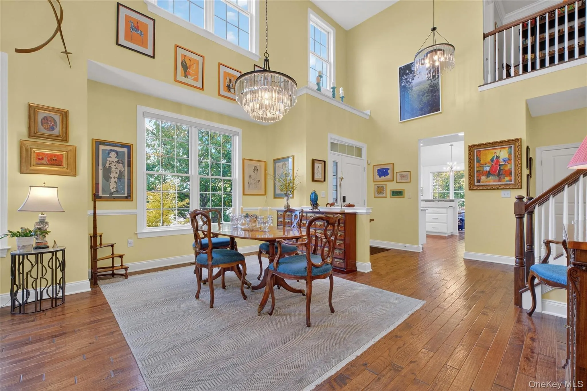 Dining space with dark wood finished floors, stairway, a towering ceiling, and a chandelier Dining space with dark wood finished floors, stairway, a towering ceiling, and a chandelier
