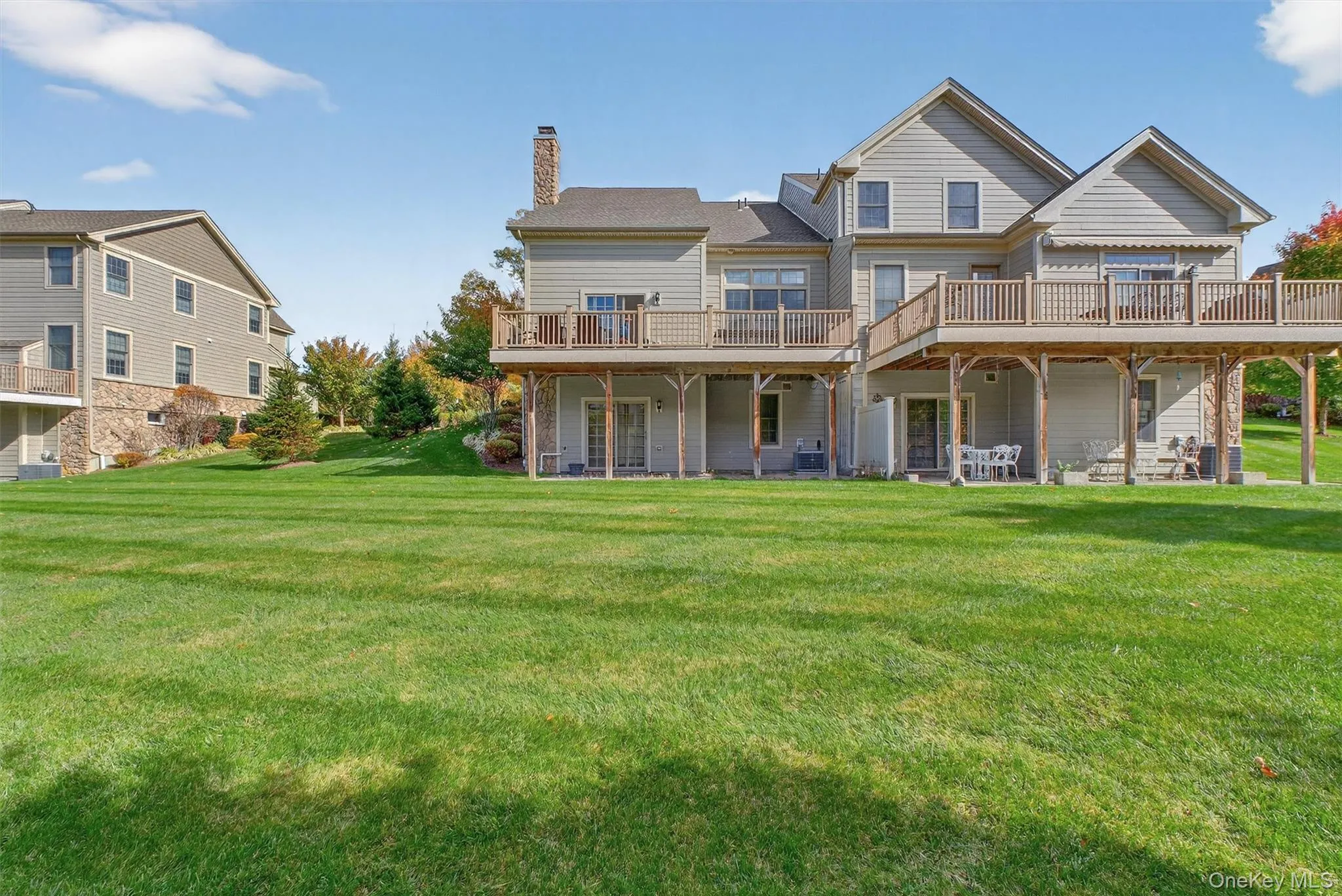 Rear view of house with a yard, a wooden deck, a chimney, and a patio area Rear view of house with a yard, a wooden deck, a chimney, and a patio area