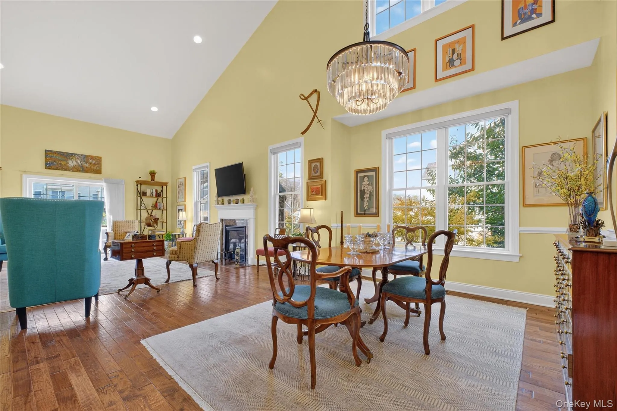 Dining space featuring high vaulted ceiling, wood-type flooring, recessed lighting, and a fireplace Dining space featuring high vaulted ceiling, wood-type flooring, recessed lighting, and a fireplace