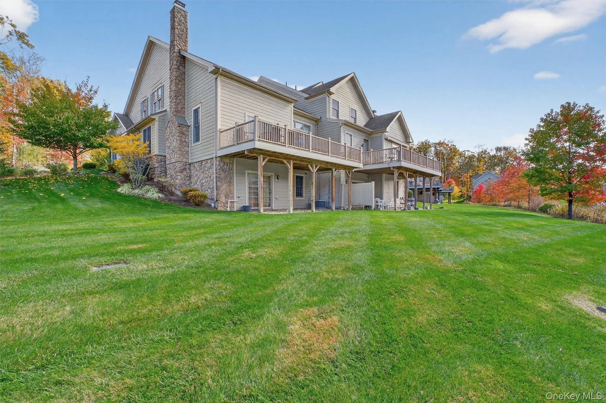 Back of house featuring a yard, a deck, a chimney, and a patio area Back of house featuring a yard, a deck, a chimney, and a patio area