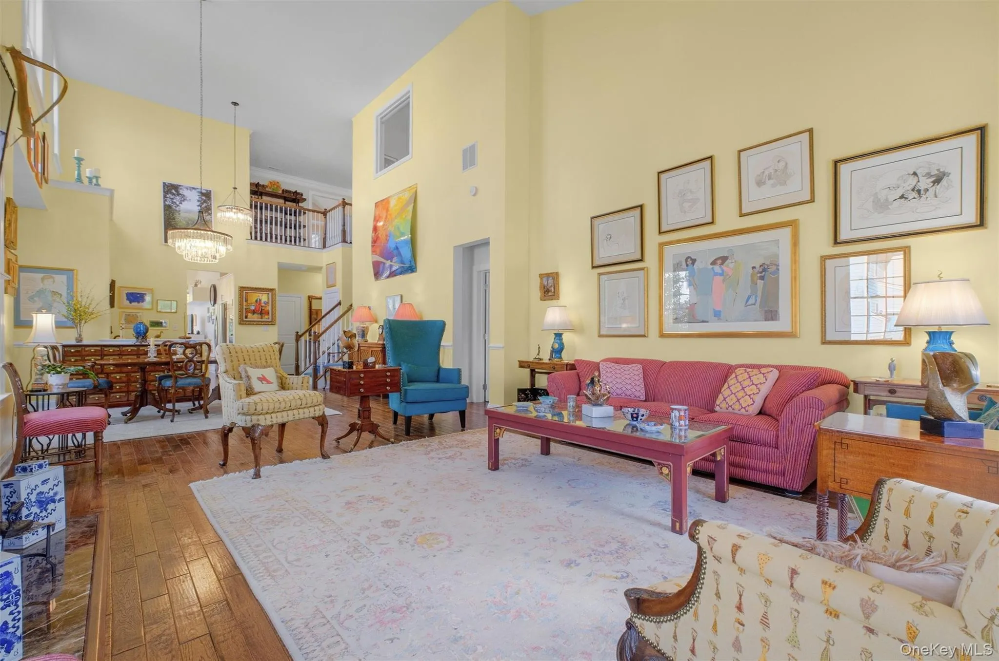 Living room featuring a high ceiling, hardwood / wood-style flooring, stairway, and crown molding Living room featuring a high ceiling, hardwood / wood-style flooring, stairway, and crown molding