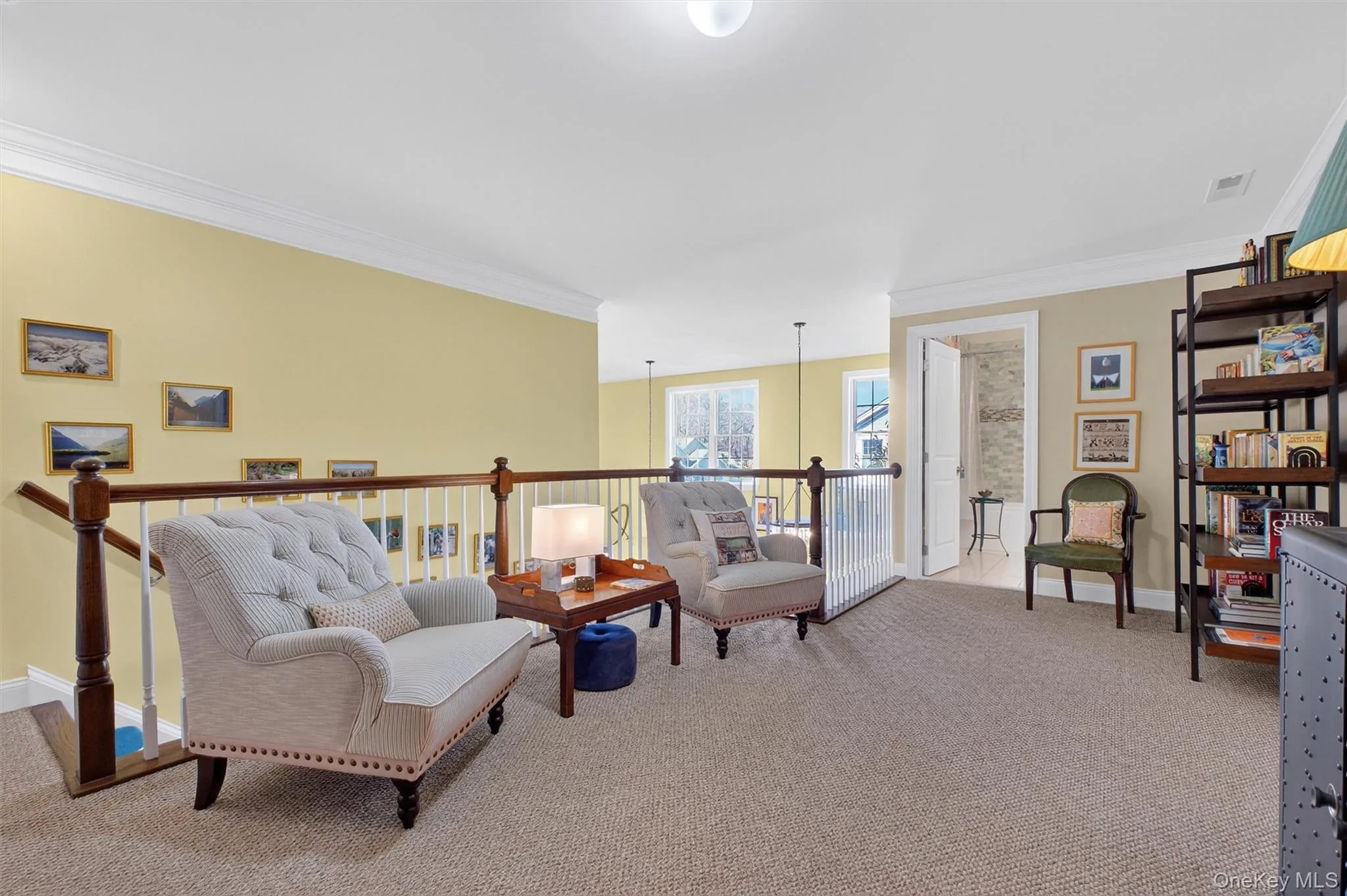 Living area with ornamental molding, light colored carpet, and an upstairs landing Living area with ornamental molding, light colored carpet, and an upstairs landing