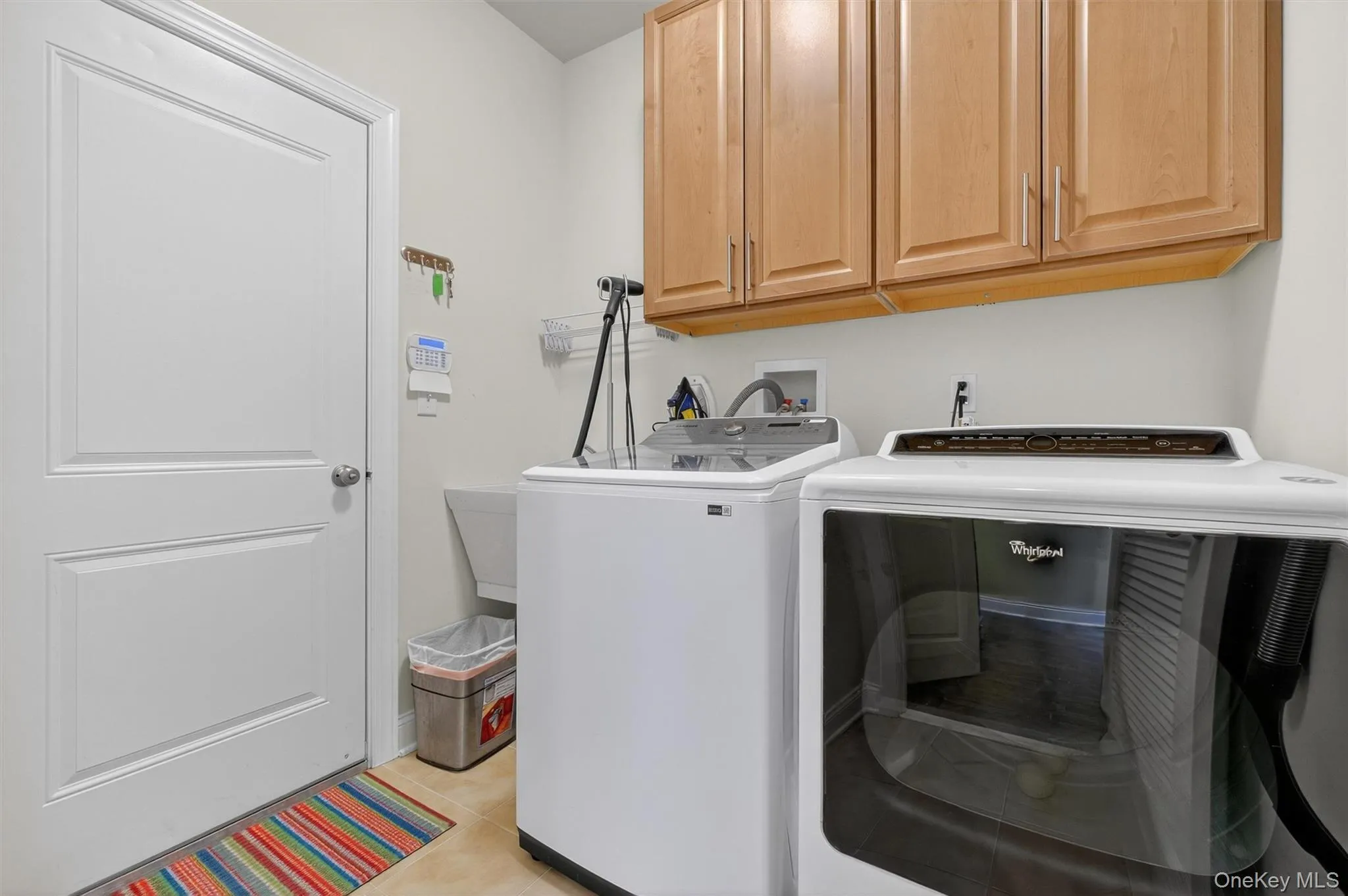 Laundry room with cabinet space, washing machine and dryer, and light tile patterned floors Laundry room with cabinet space, washing machine and dryer, and light tile patterned floors