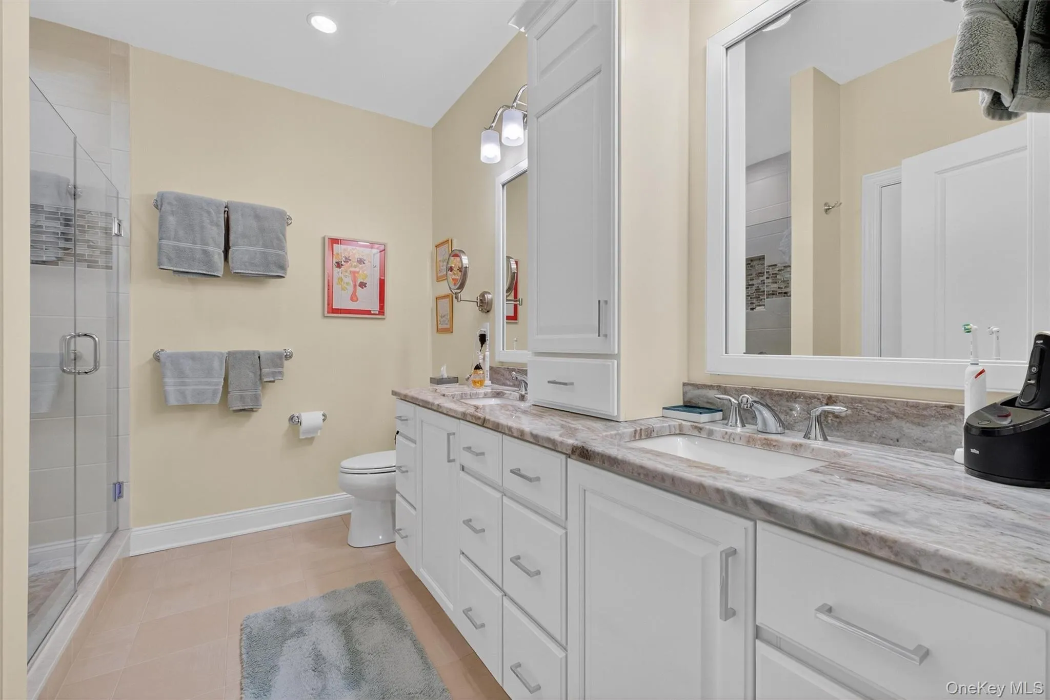 Bathroom featuring double vanity, a shower stall, recessed lighting, and light tile patterned flooring Bathroom featuring double vanity, a shower stall, recessed lighting, and light tile patterned flooring