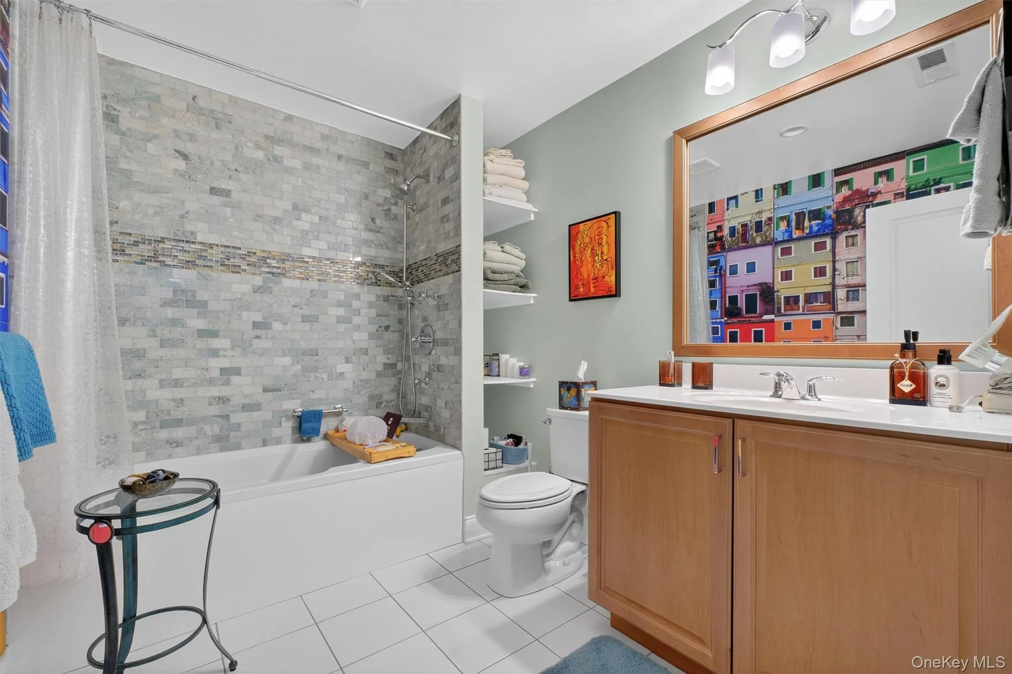 Full bathroom featuring shower / bath combo with shower curtain, light tile patterned floors, and vanity Full bathroom featuring shower / bath combo with shower curtain, light tile patterned floors, and vanity