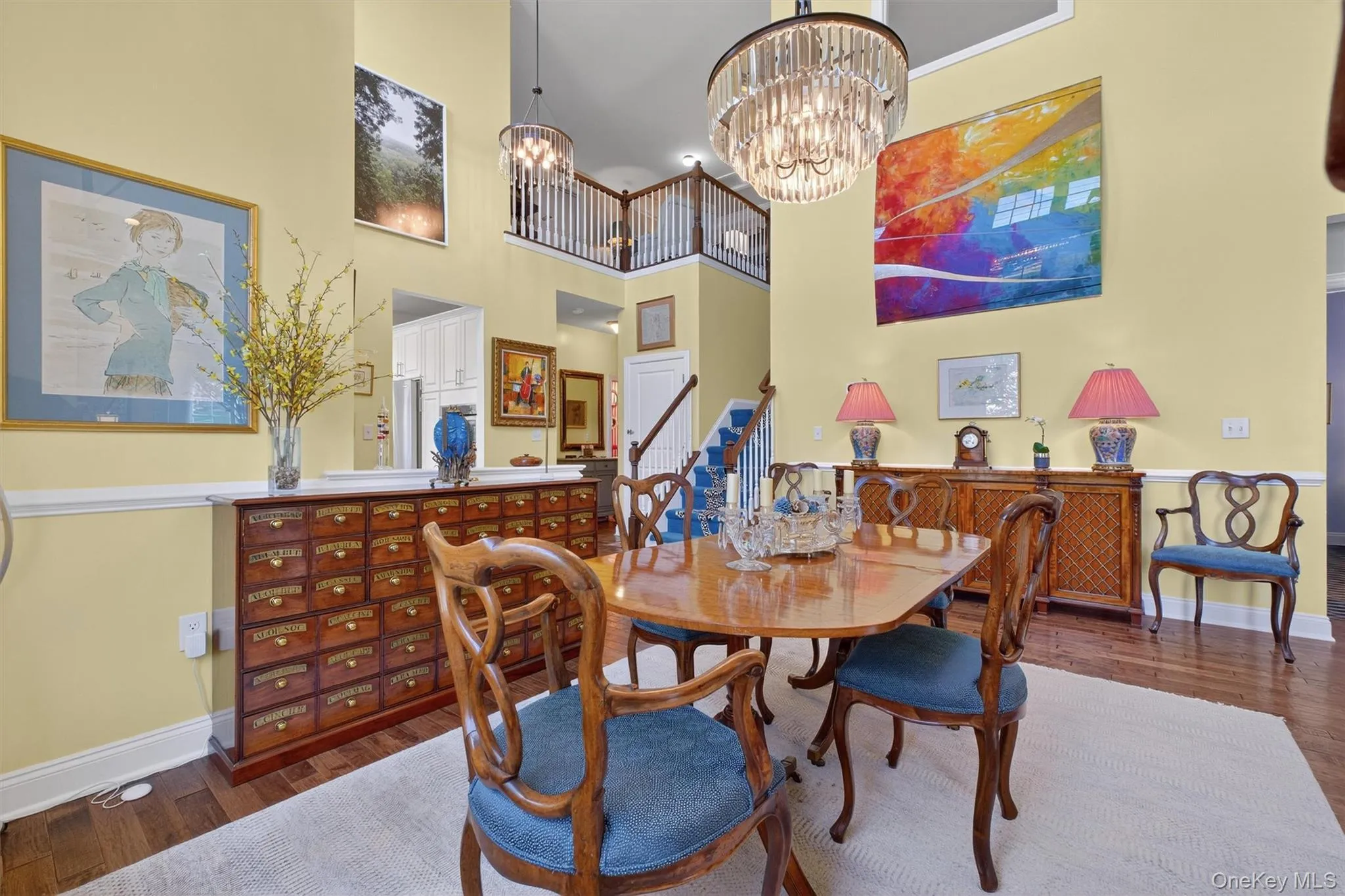 Dining room with dark wood-style flooring, a chandelier, a high ceiling, and stairway Dining room with dark wood-style flooring, a chandelier, a high ceiling, and stairway