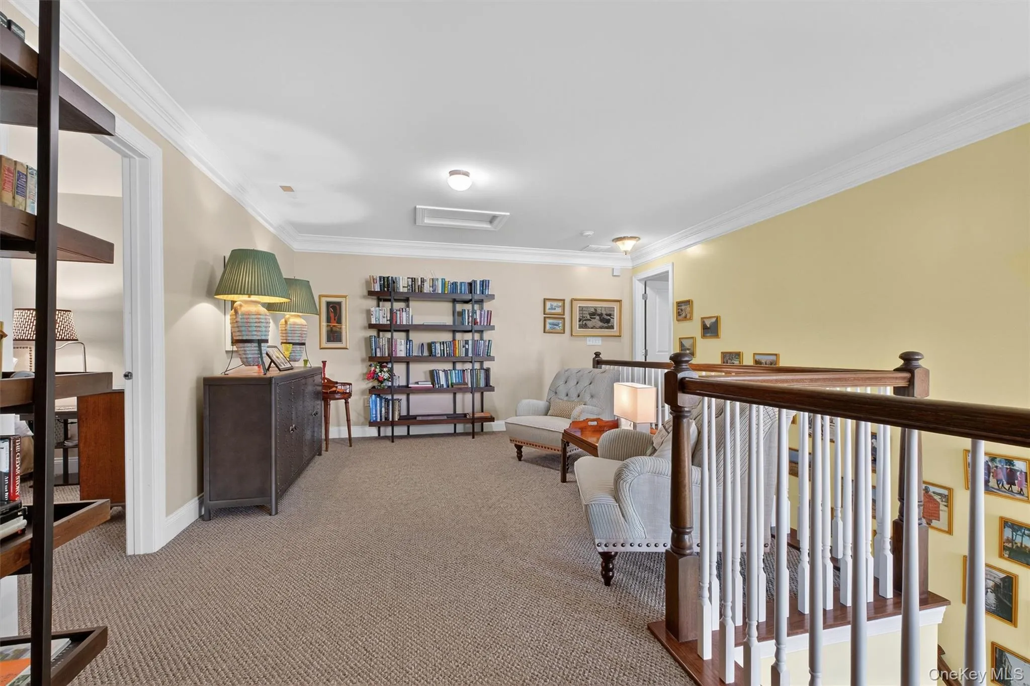 Living area featuring attic access, crown molding, and carpet Living area featuring attic access, crown molding, and carpet