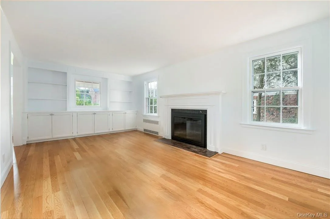 Bright, sunny Living Room with wood burning fireplace, built-in bookshelves and cabinets looking out to front brick porch and large front lawn. Bright, sunny Living Room with wood burning fireplace, built-in bookshelves and cabinets looking out to front brick porch and large front lawn.