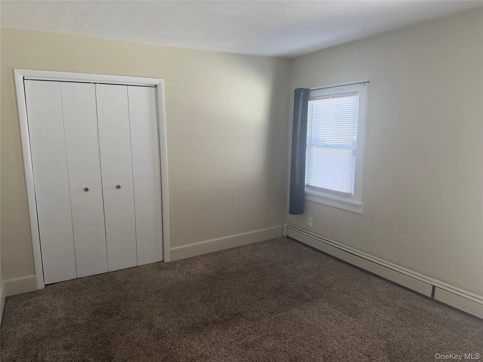 Primary bedroom with baseboard heating, fresh carpet , fresh paint, and a third closet. Primary bedroom with baseboard heating, fresh carpet , fresh paint, and a third closet.