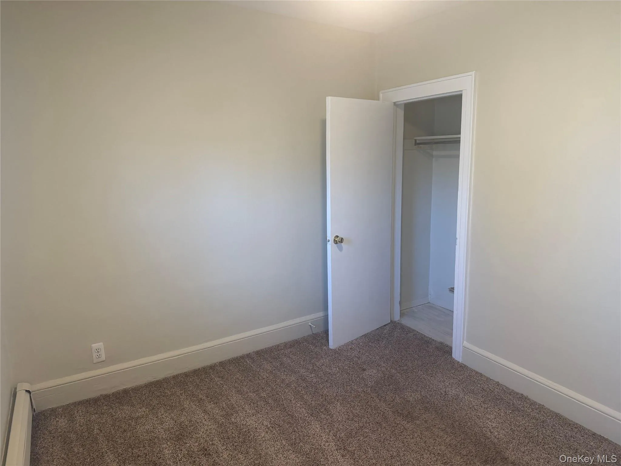 Unfurnished 2nd bedroom with carpet, a closet, and baseboard heating Unfurnished 2nd bedroom with carpet, a closet, and baseboard heating
